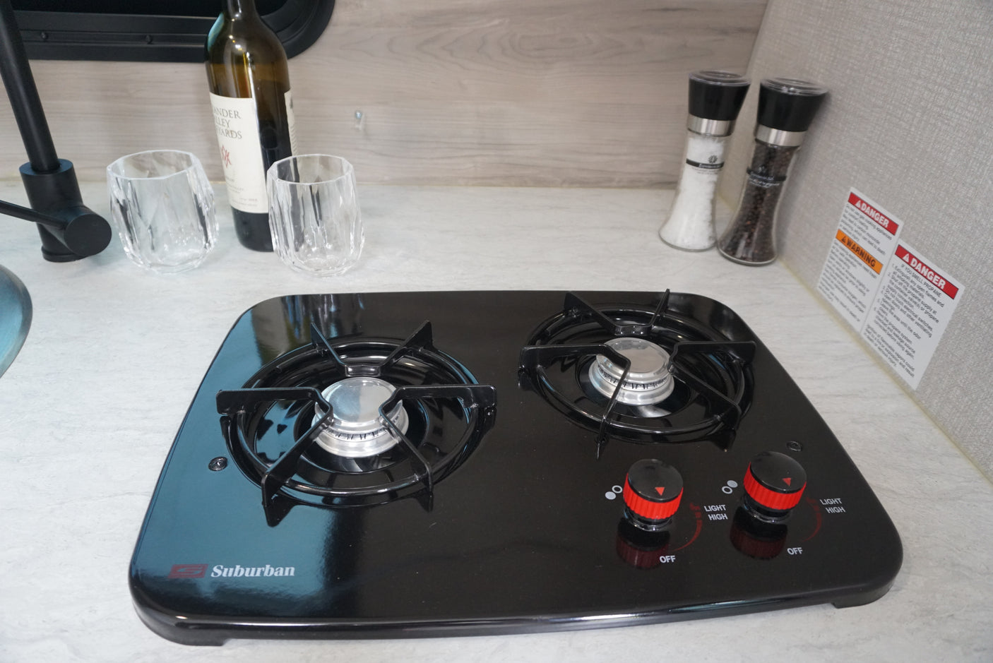 This RV rental kitchen has a clean two-burner gas stove, ready for cooking, with wine and spices nearby.