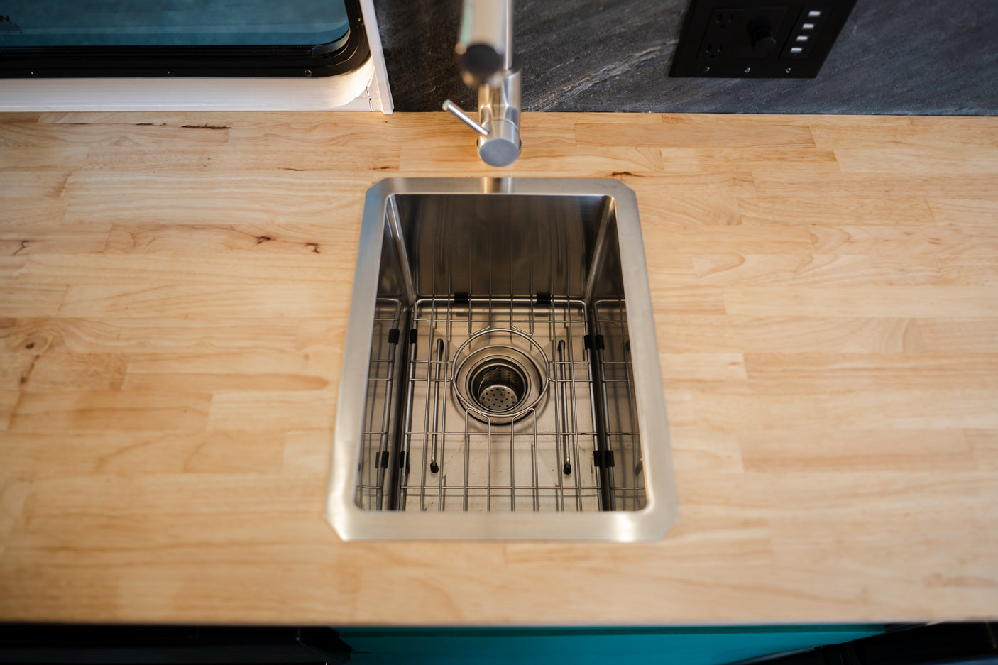 RV rental kitchen sink area with a stainless steel basin, modern faucet, and light wood countertop.