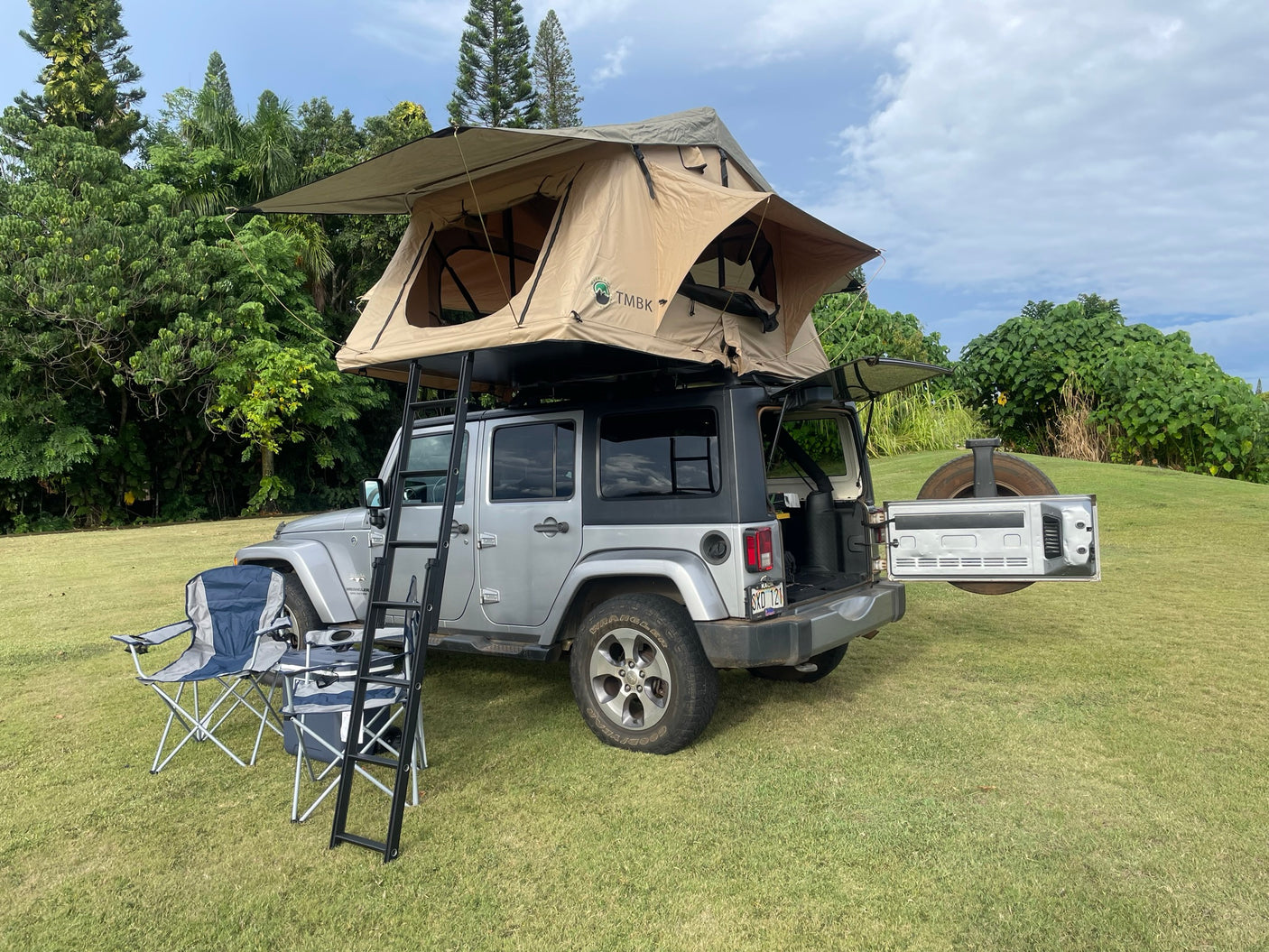 Silver Jeep Wrangler with a TMBK rooftop tent deployed, offering a compact RV rental camping solution.