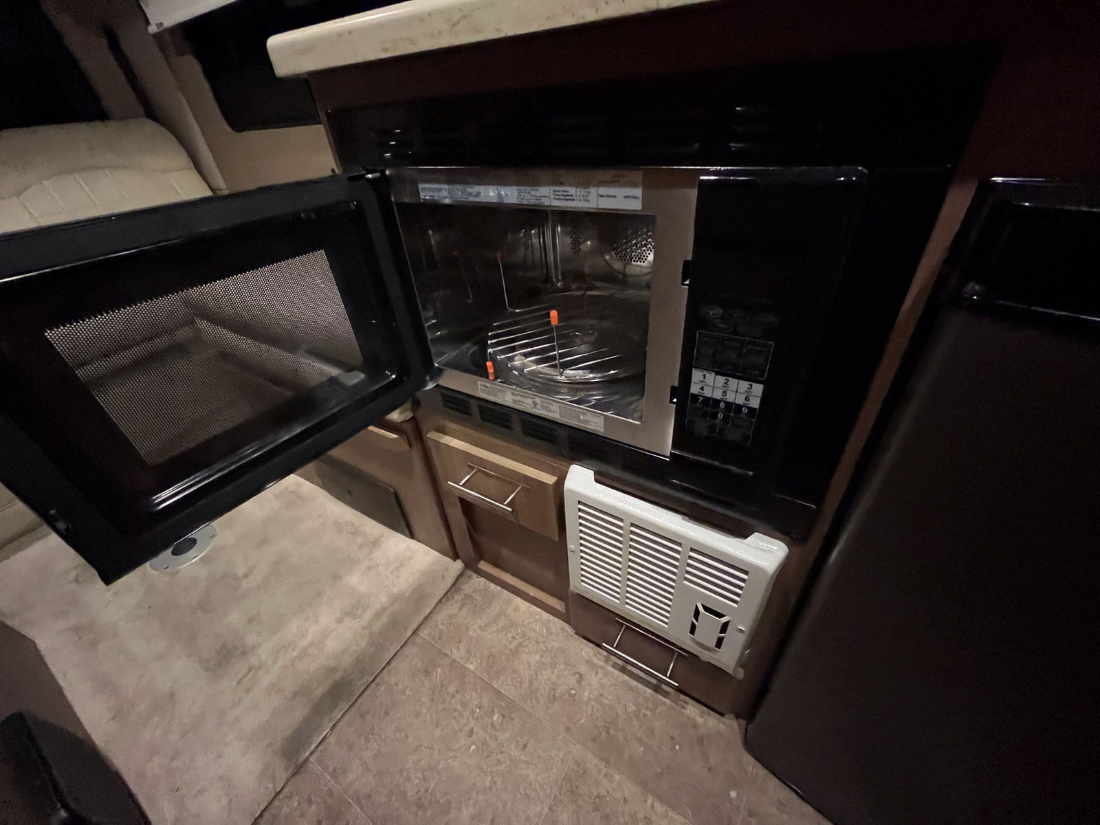 and a wall-mounted TV.|Compact RV rental interior featuring a kitchen with sink/stove