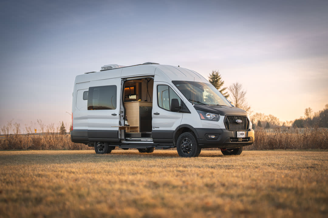 and integrated shower/toilet wet bath.|RV rental interior: A bed with blue bedding and a book