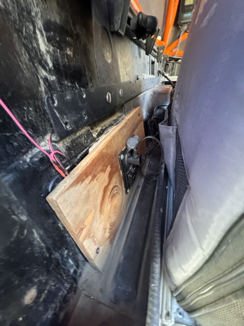 RV rental interior: A custom wooden board with mounted gear, secured beside the vehicle seat.