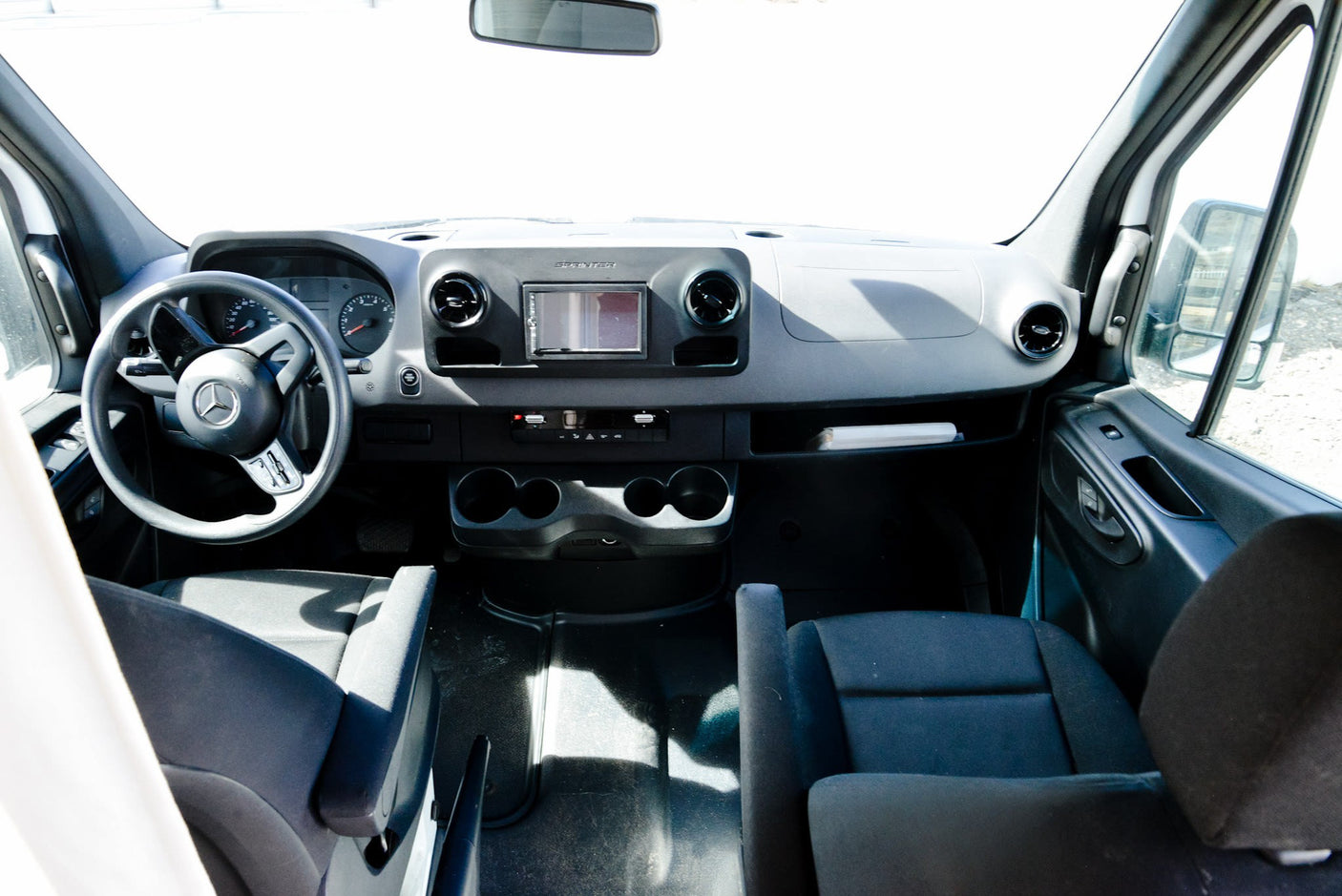 rv rental Mercedes-Benz Sprinter van interior: dashboard, steering wheel, infotainment system, and front seats are clearly visible.