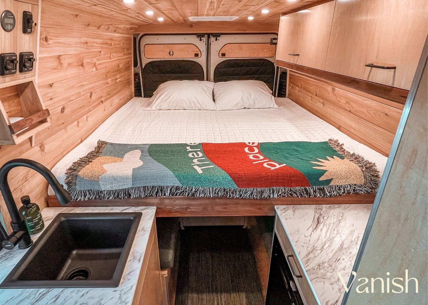 and a convertible dinette/table with a sink nearby.|Cozy RV rental interior: a large bed