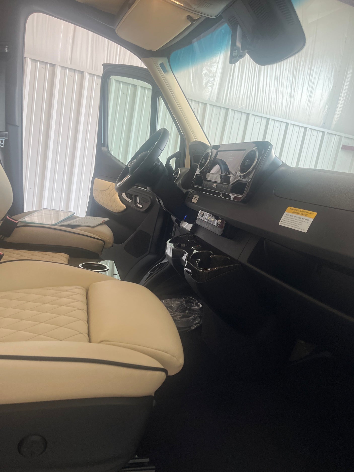 RV rental interior: Cream quilted seats, modern black dashboard, and steering wheel of a spacious van.