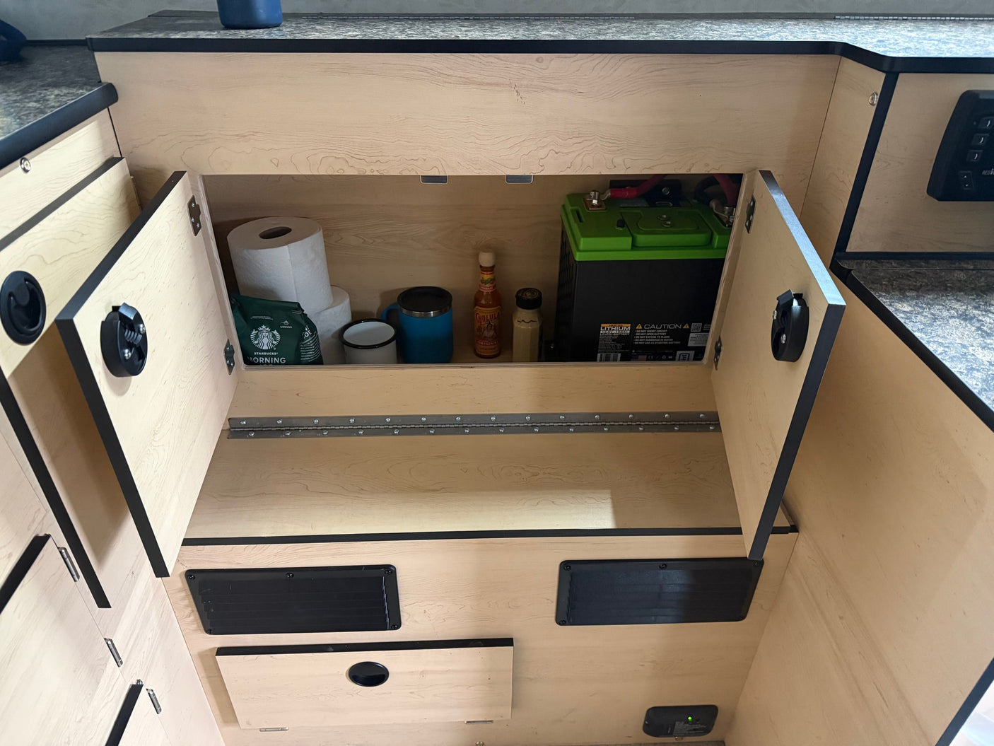 RV rental storage compartment: organized with coffee, essentials, and a crucial lithium battery for off-grid adventures.