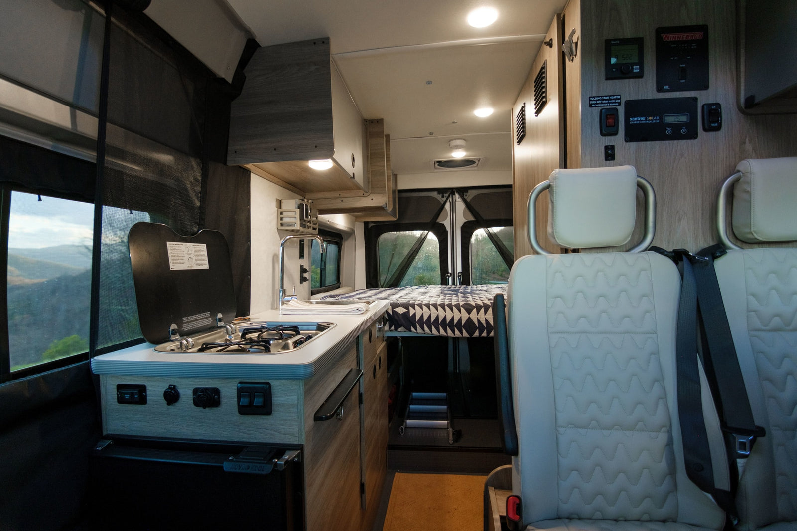 and storage for road trip comfort.|This rv rental showcases a compact kitchen with stove and sink