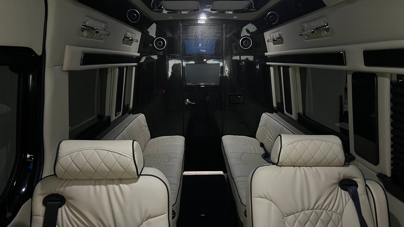 Premium rv rental interior with facing quilted seats, ceiling speakers, and entertainment screen for comfort.