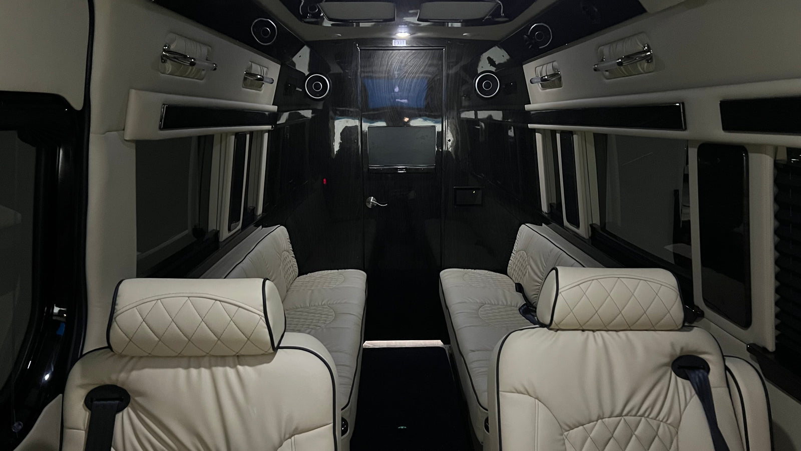 Premium rv rental interior with facing quilted seats, ceiling speakers, and entertainment screen for comfort.