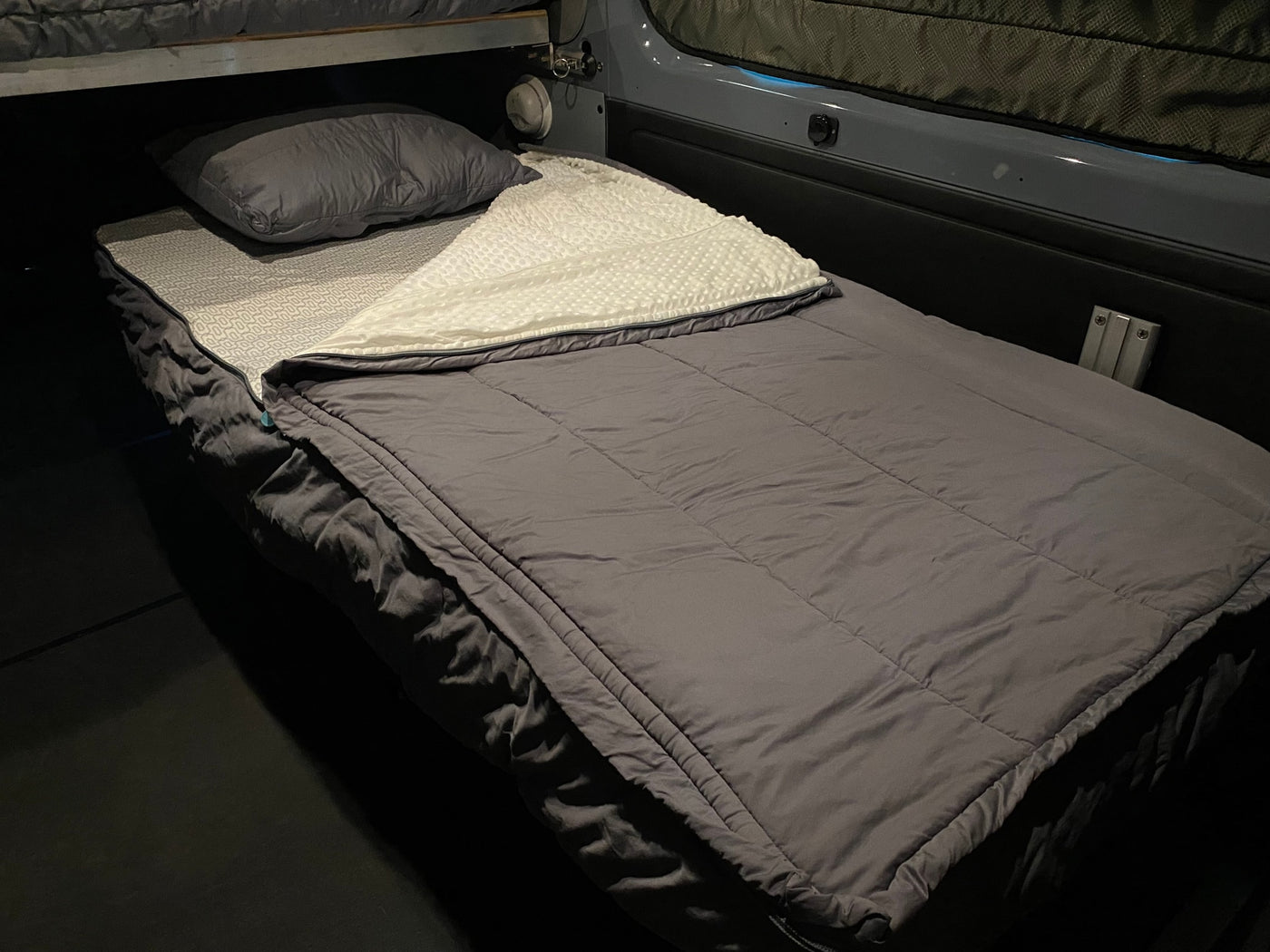 Experience comfort in this cozy RV rental bed, complete with a grey comforter, textured white blanket, and pillow. — photo 16