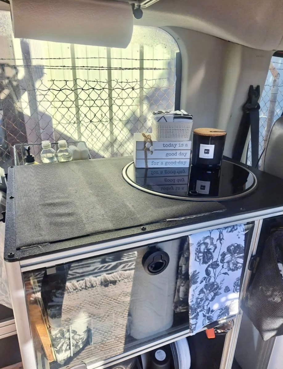 Compact RV rental kitchen setup with sink, storage, and cozy decor, perfect for mobile living.