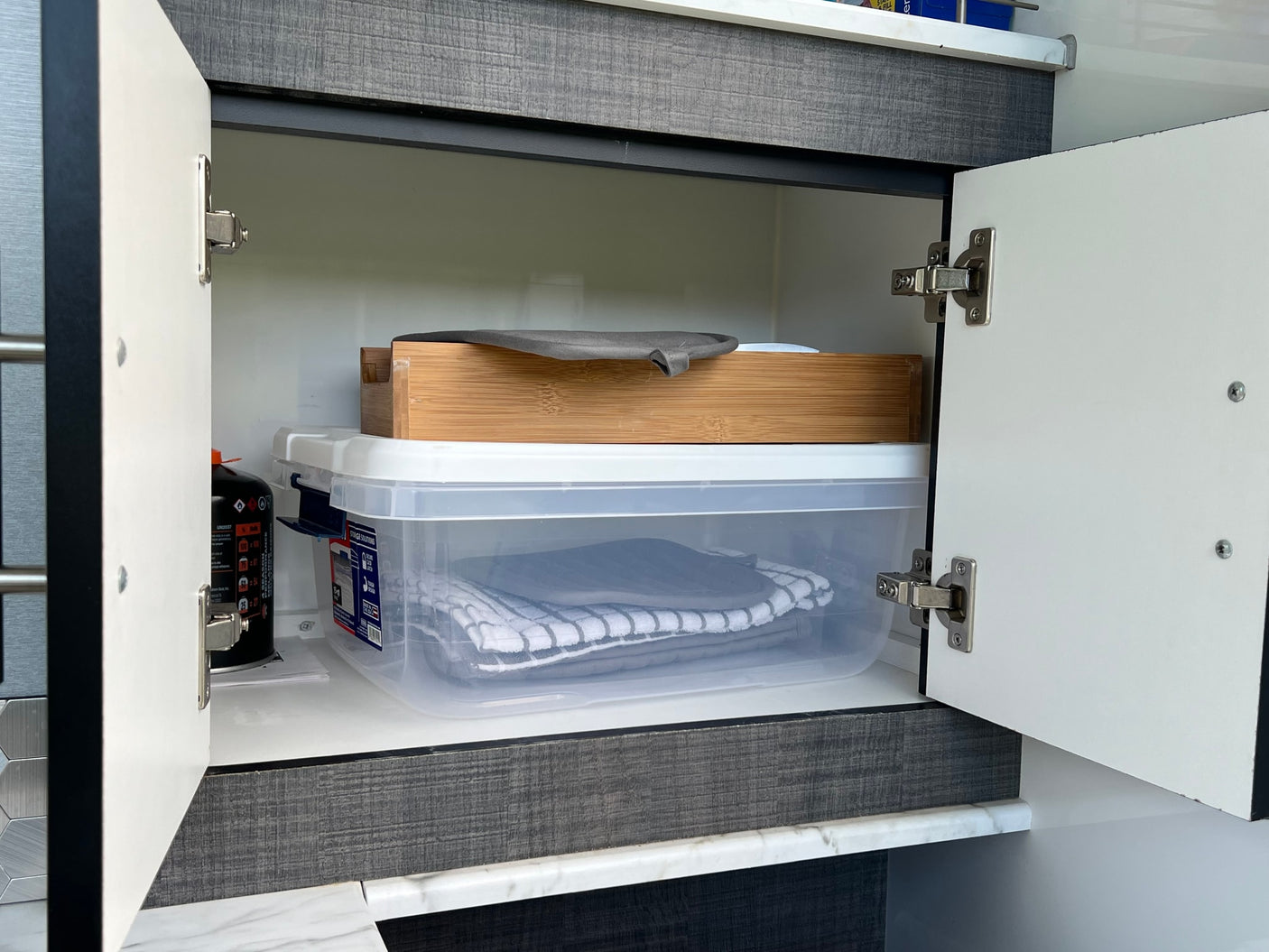 and open kitchen hatch.|Compact RV rental teardrop trailer shows its fully equipped mobile kitchen with blue lights