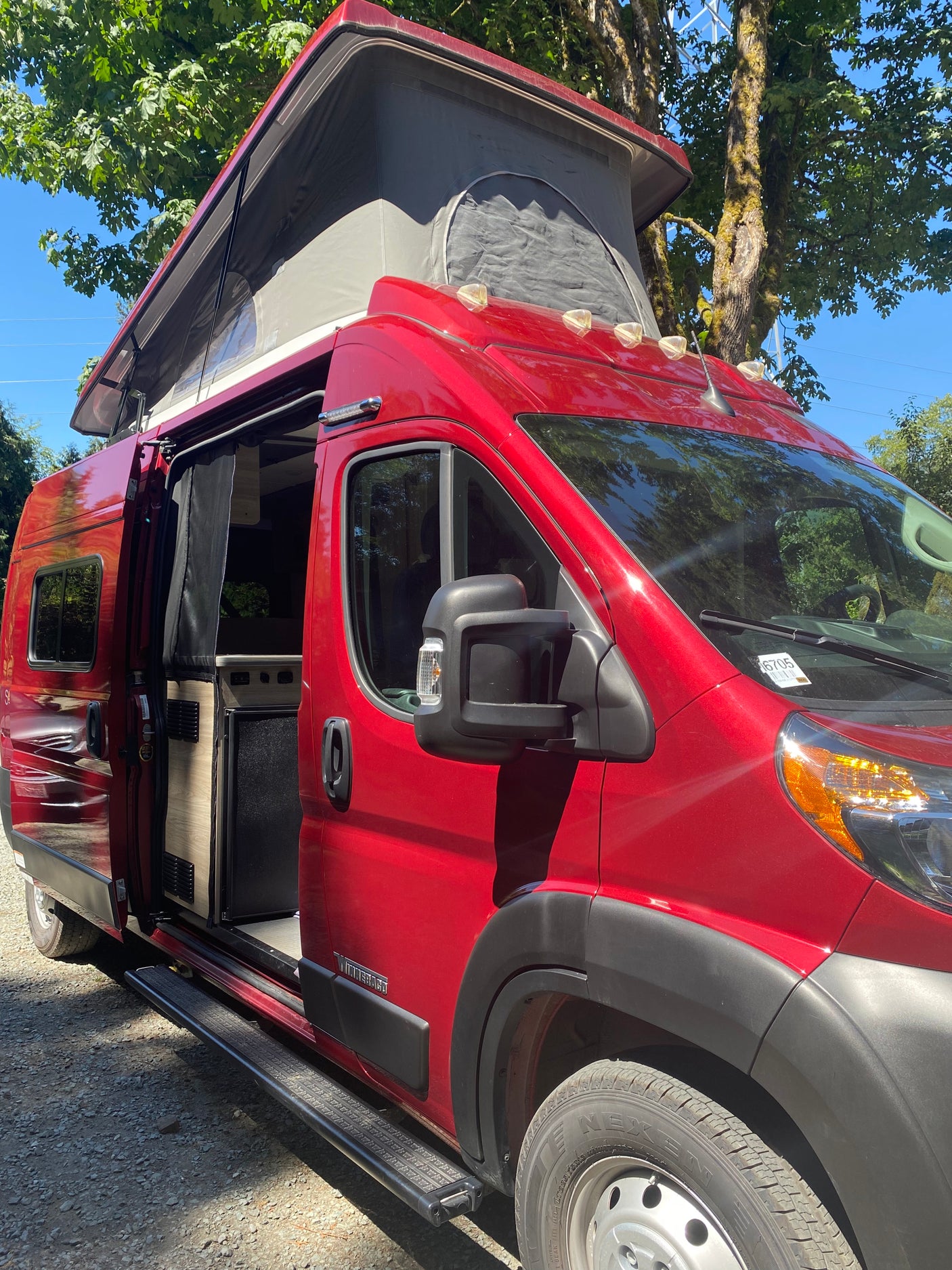 Explore in this red pop-top camper van, an ideal rv rental. Side door open shows the inviting interior.