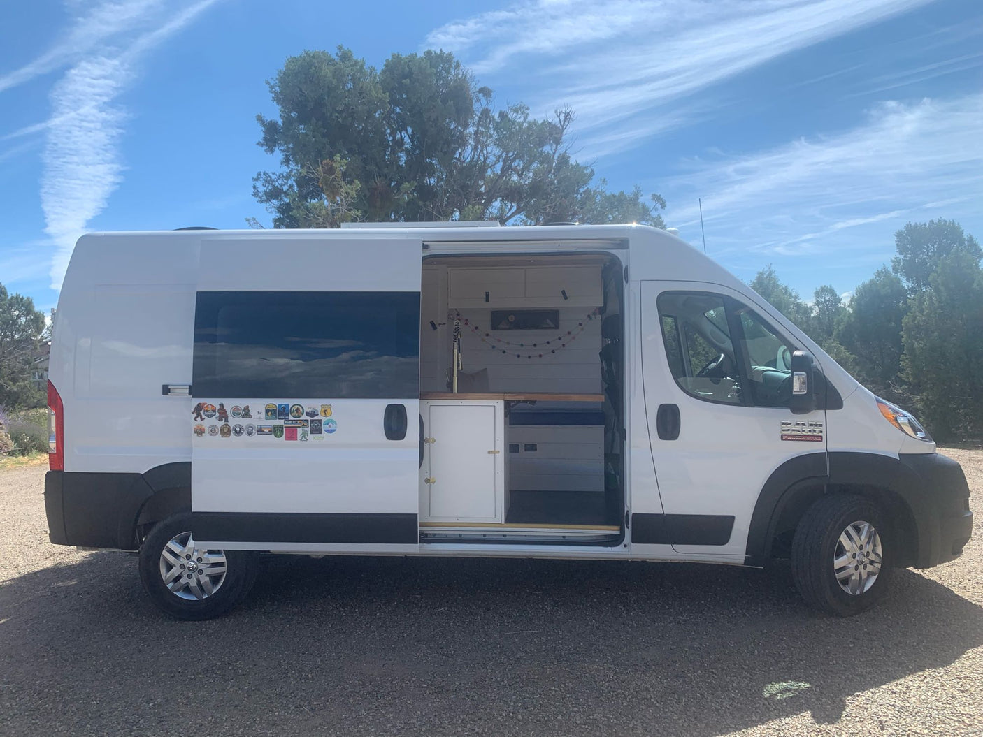 White camper van, side door open to reveal a custom-built interior. A versatile RV rental for road trips.