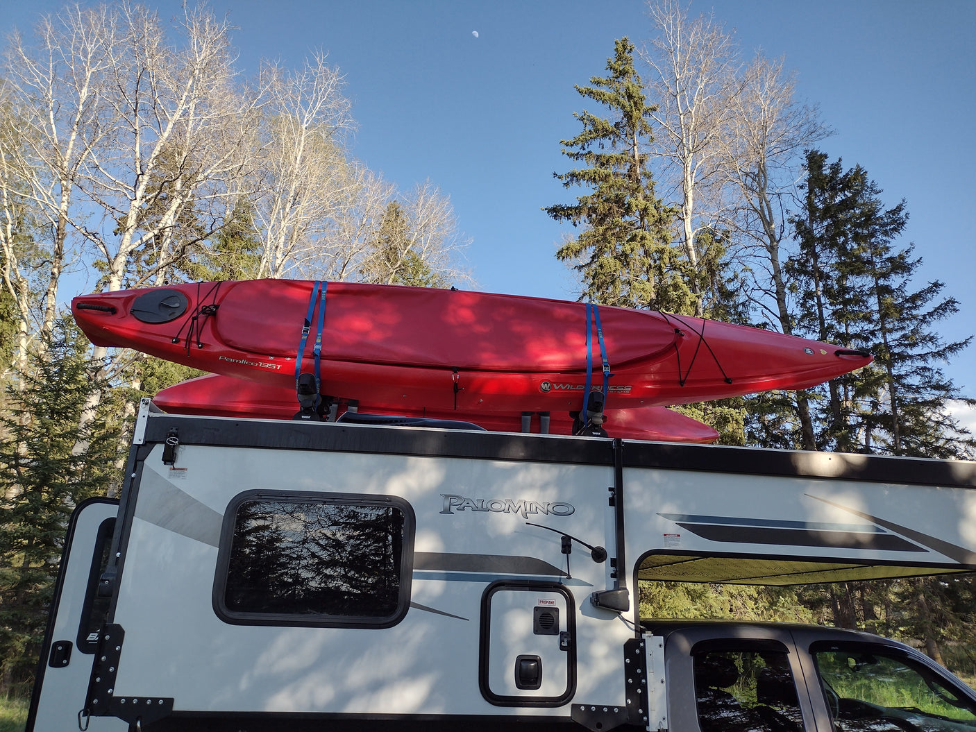 Two red kayaks strapped atop an **rv rental** truck camper, ready for wilderness travel and water sports adventures.