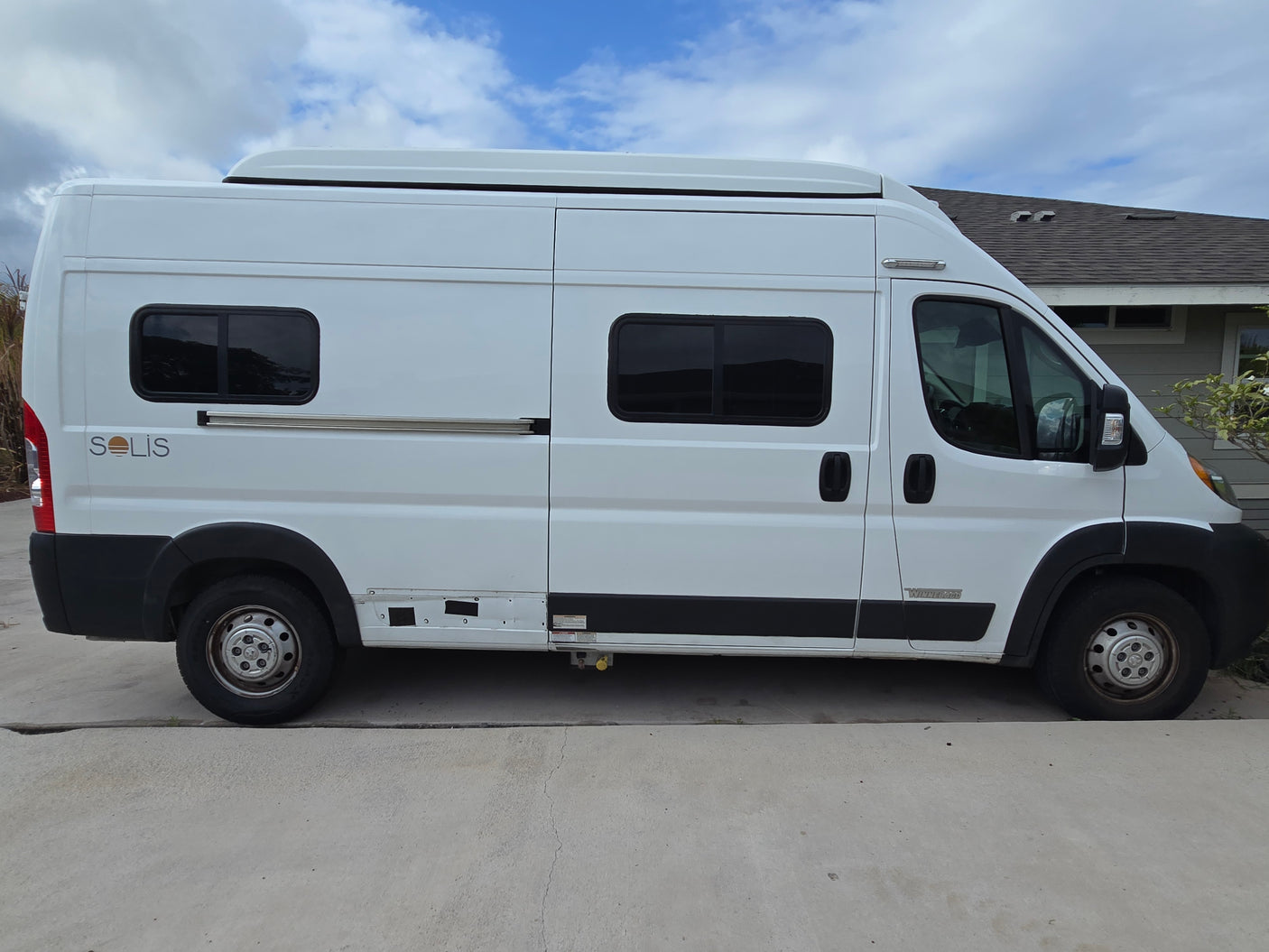 A white Winnebago Solis camper van, perfect for RV rental, parked on concrete outdoors under a blue sky.