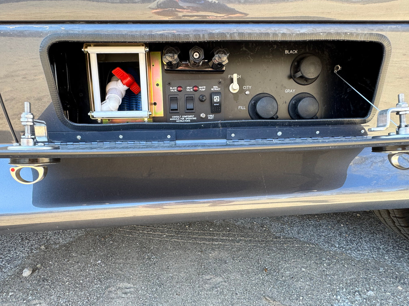 RV rental: detailed view of the utility bay with fresh/city water, black/gray tank, and cable hookup panel.