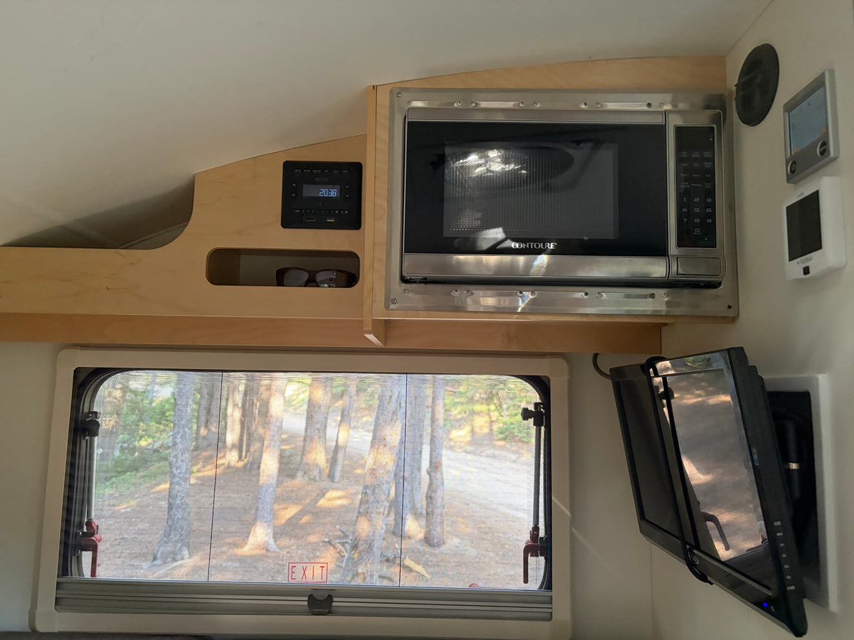 and forest views outside.|RV rental bedroom featuring a bed with quilted blue blanket — photo 12