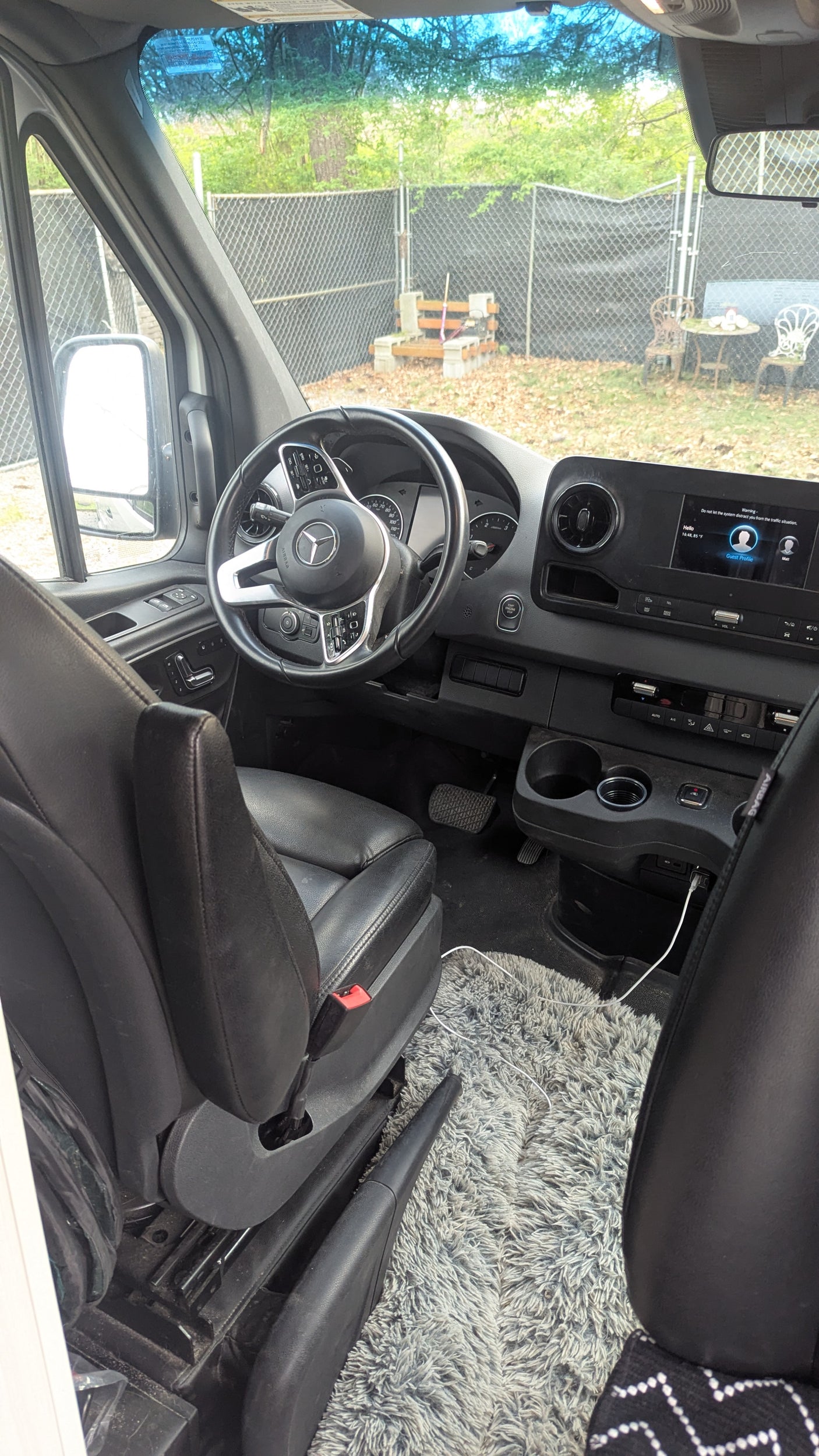 Driver's view of an RV rental van interior: steering wheel, dashboard with infotainment screen, and comfortable seat.