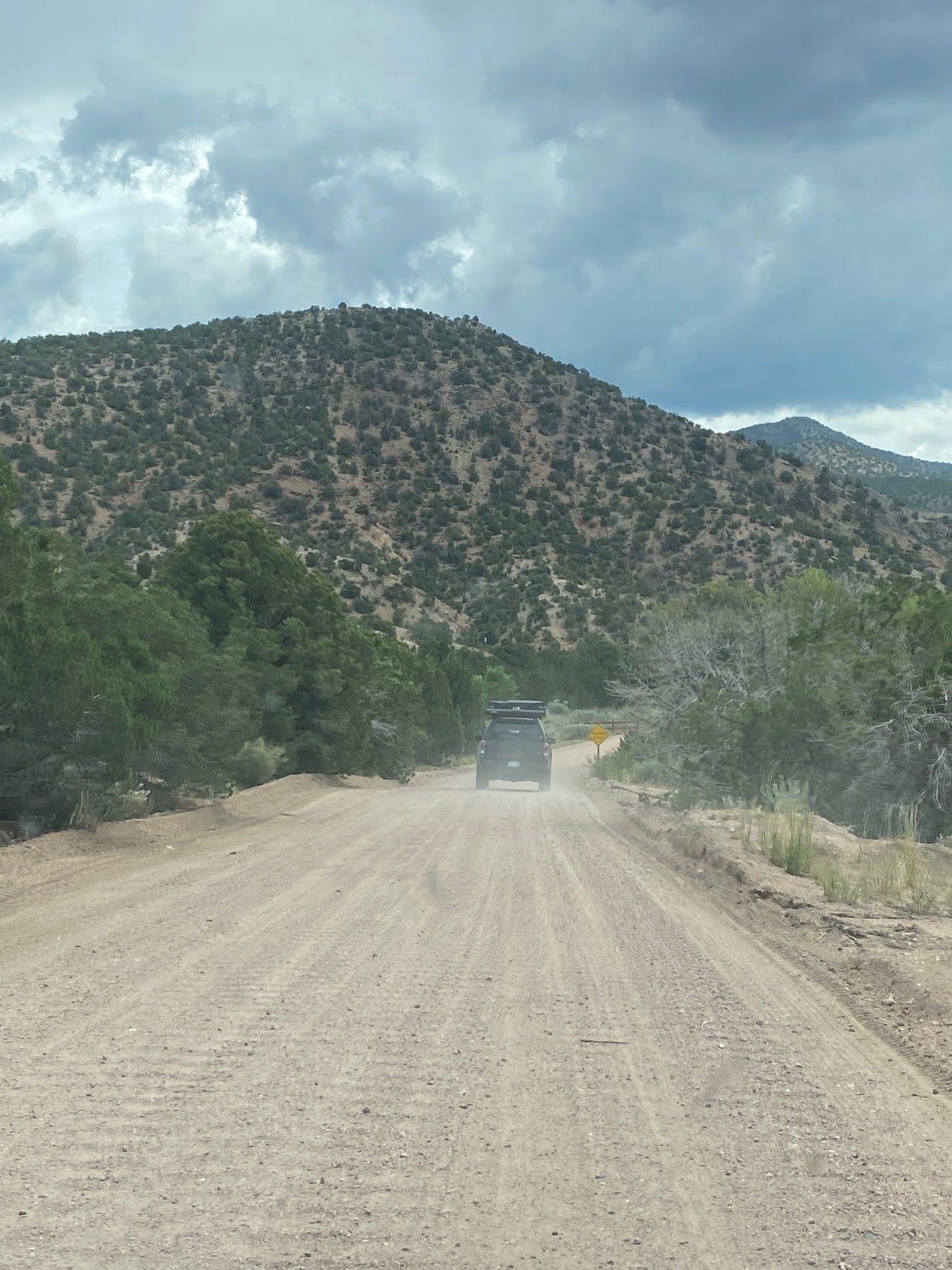 set against sunlit mountains and trees.|Adventure awaits with this truck & rooftop tent — photo 1