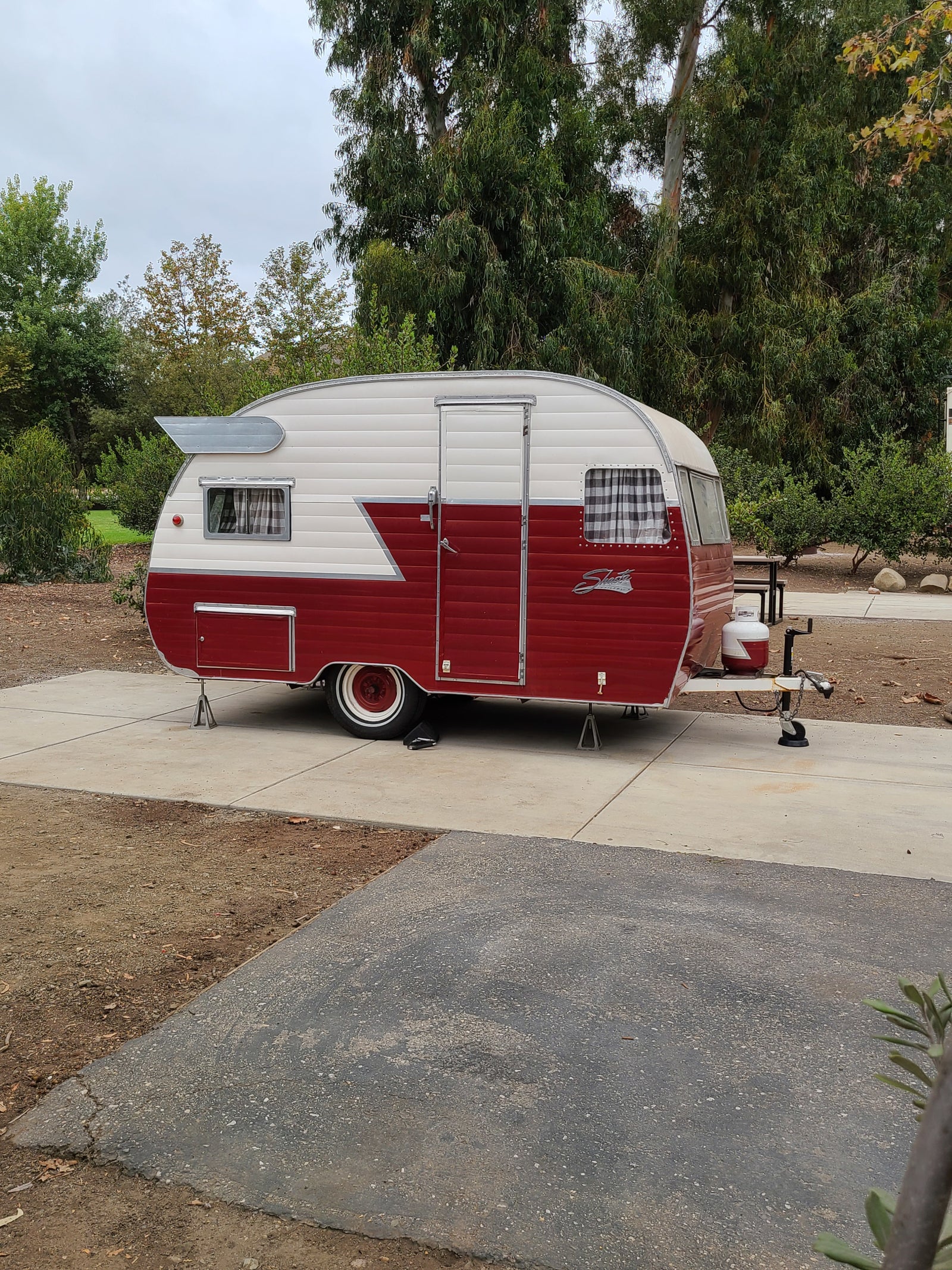Retro red & white Shasta travel trailer, parked at a campsite, ready for your next RV rental adventure.