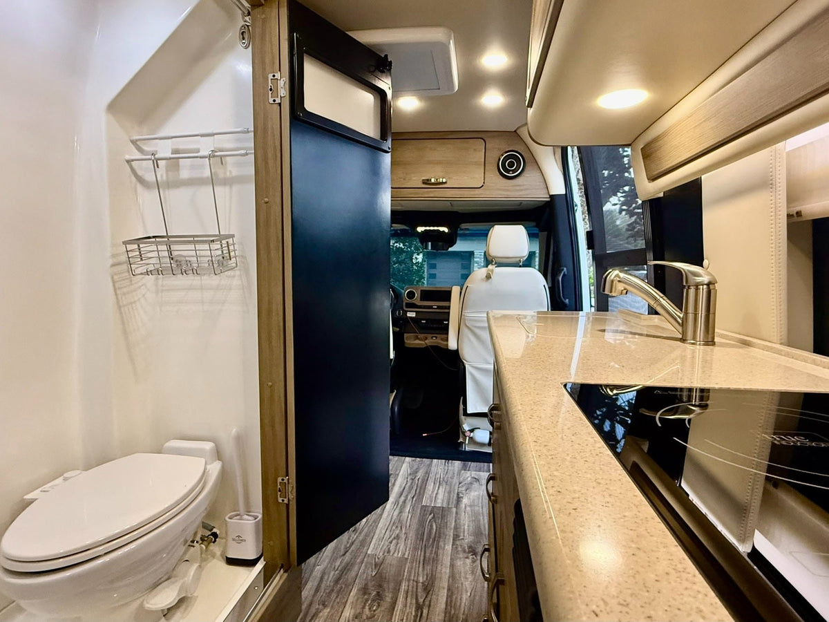 and overhead cabinets.|Comfortable RV rental interior featuring a large bed — photo 19