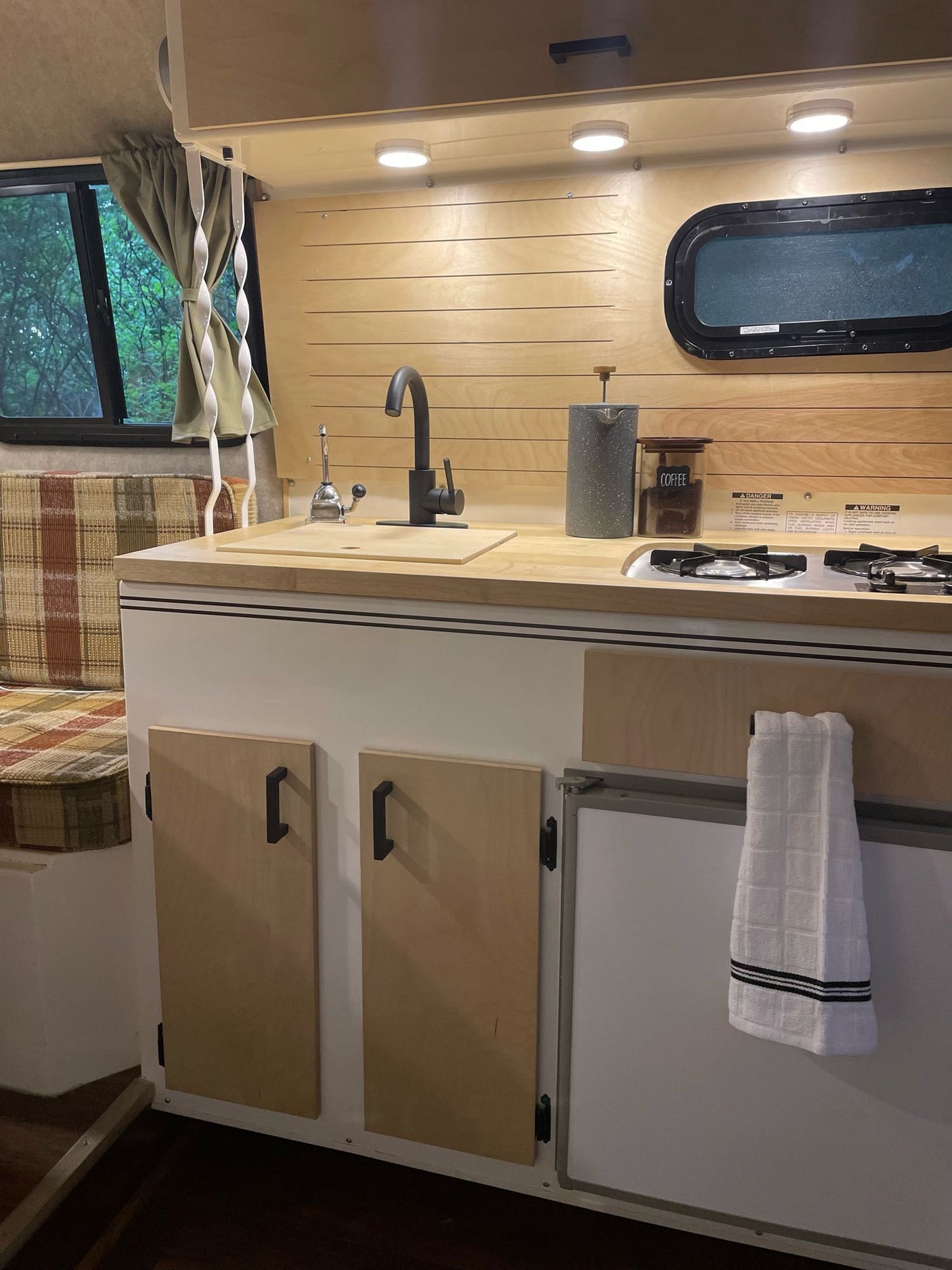 & chairs next to a red SUV.|A woman holds her baby inside a cozy white Scamp camper