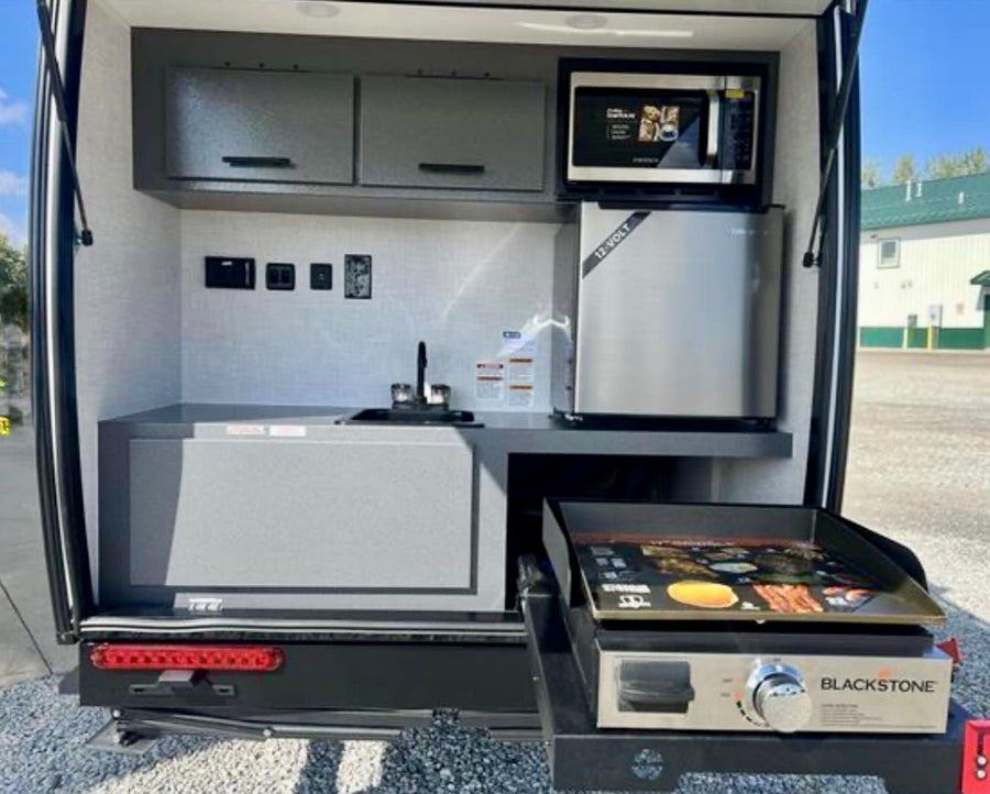 is ready for adventure.|Interior of a compact RV rental featuring two grey upholstered beds/benches