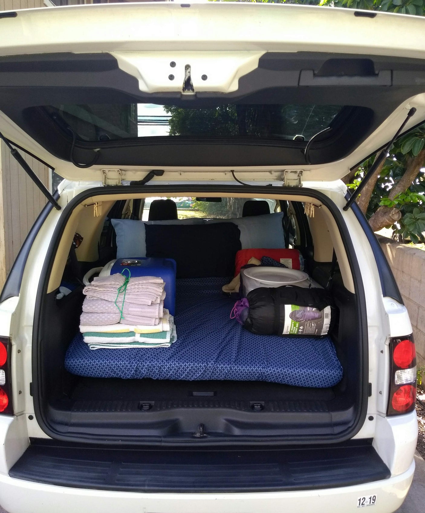 White SUV trunk showing a sleeping setup with mattress & sleeping bag – a smart alternative to an RV rental for car camping.