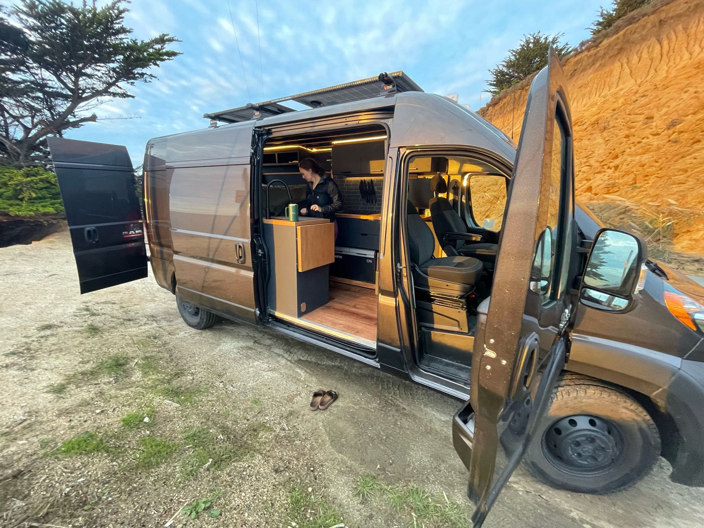 Explore in comfort with this RV rental! Woman makes coffee in a modern camper van kitchen