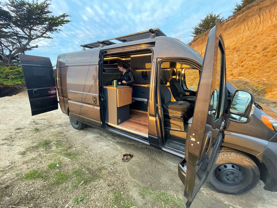 Explore in comfort with this RV rental! Woman makes coffee in a modern camper van kitchen