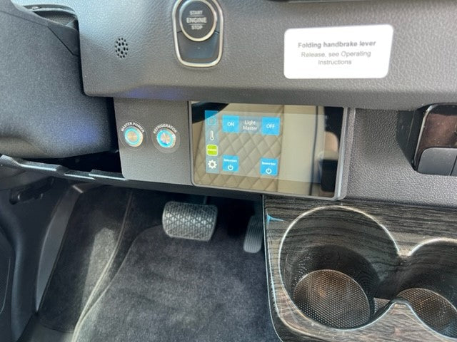 RV rental interior: driver's console showing main power, refrigerator buttons, digital display, pedals, and engine start.