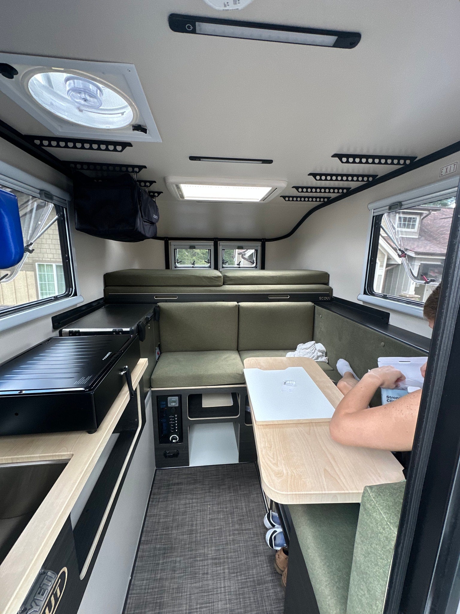 Experience compact living in this modern RV rental interior with a kitchenette, dining, and sleeping areas, perfect for adventure.