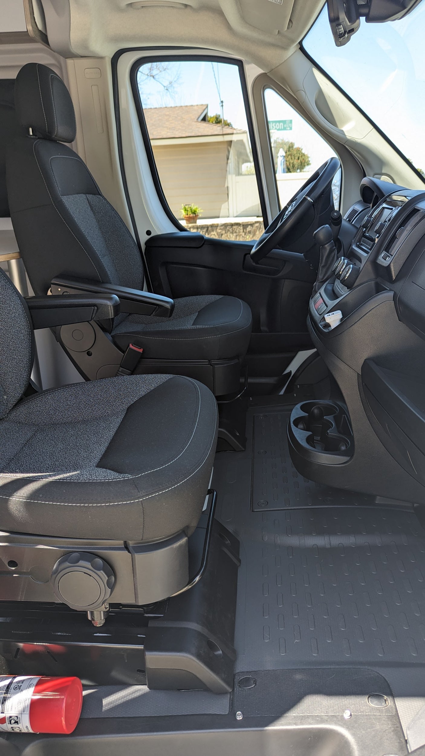 RV rental van's front cabin. Features swiveling seats, dashboard, cup holders, and a fire extinguisher for safety.