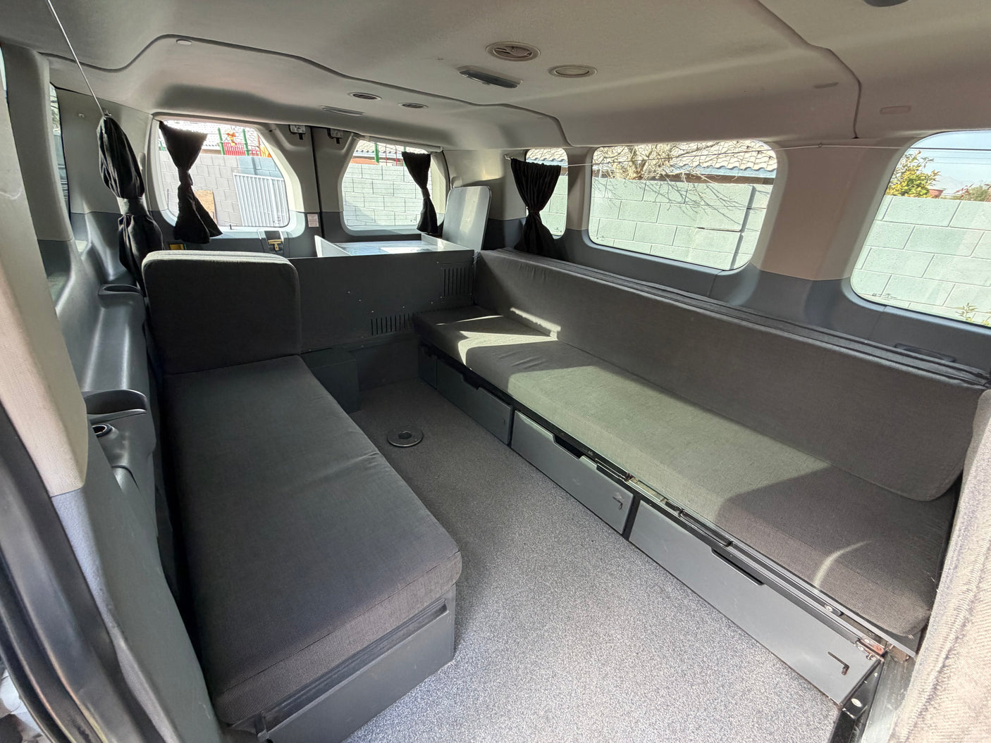 RV rental's custom camper van interior: comfortable bench seating, convertible sleeping area, and practical under-seat storage.