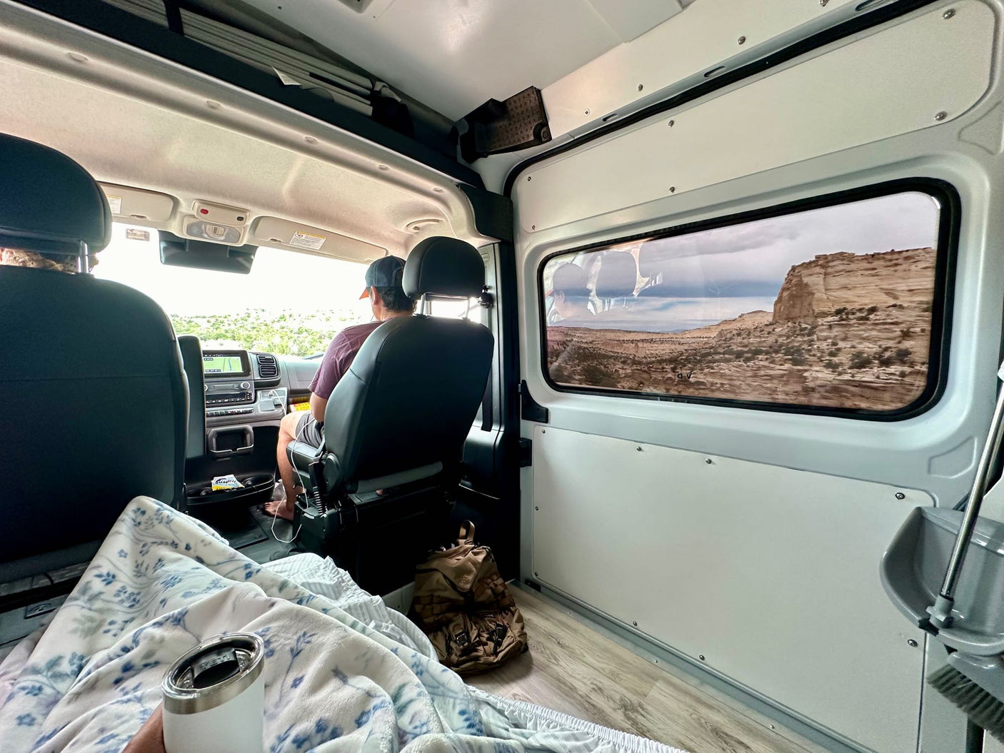 Cozy RV rental interior on a scenic road trip, with desert mesas visible through the side window.