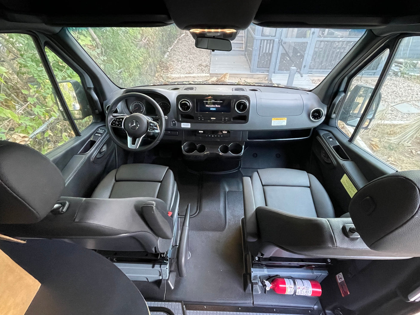 Experience a clean Mercedes-Benz Sprinter rv rental. Wide-angle view of the modern cockpit, dashboard, and front seats.