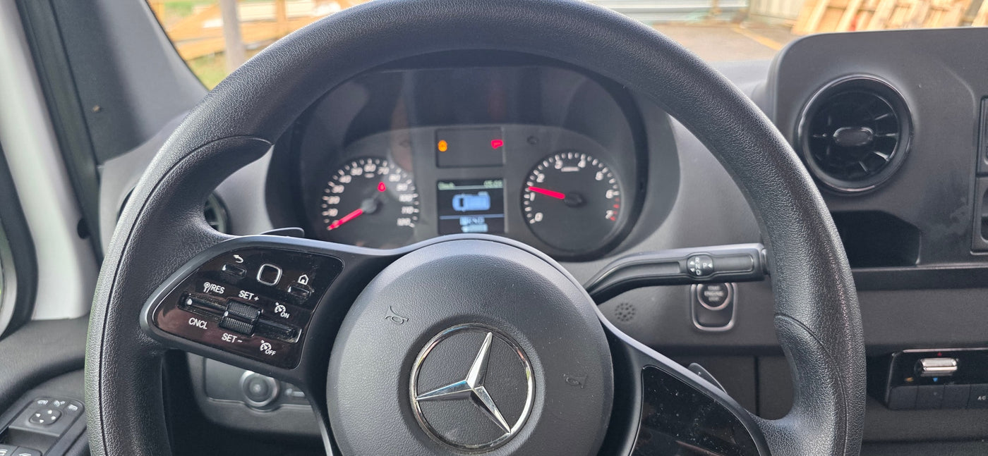 Inside a Mercedes-Benz RV rental: steering wheel, dashboard, controls, and illuminated gauges. — photo 7