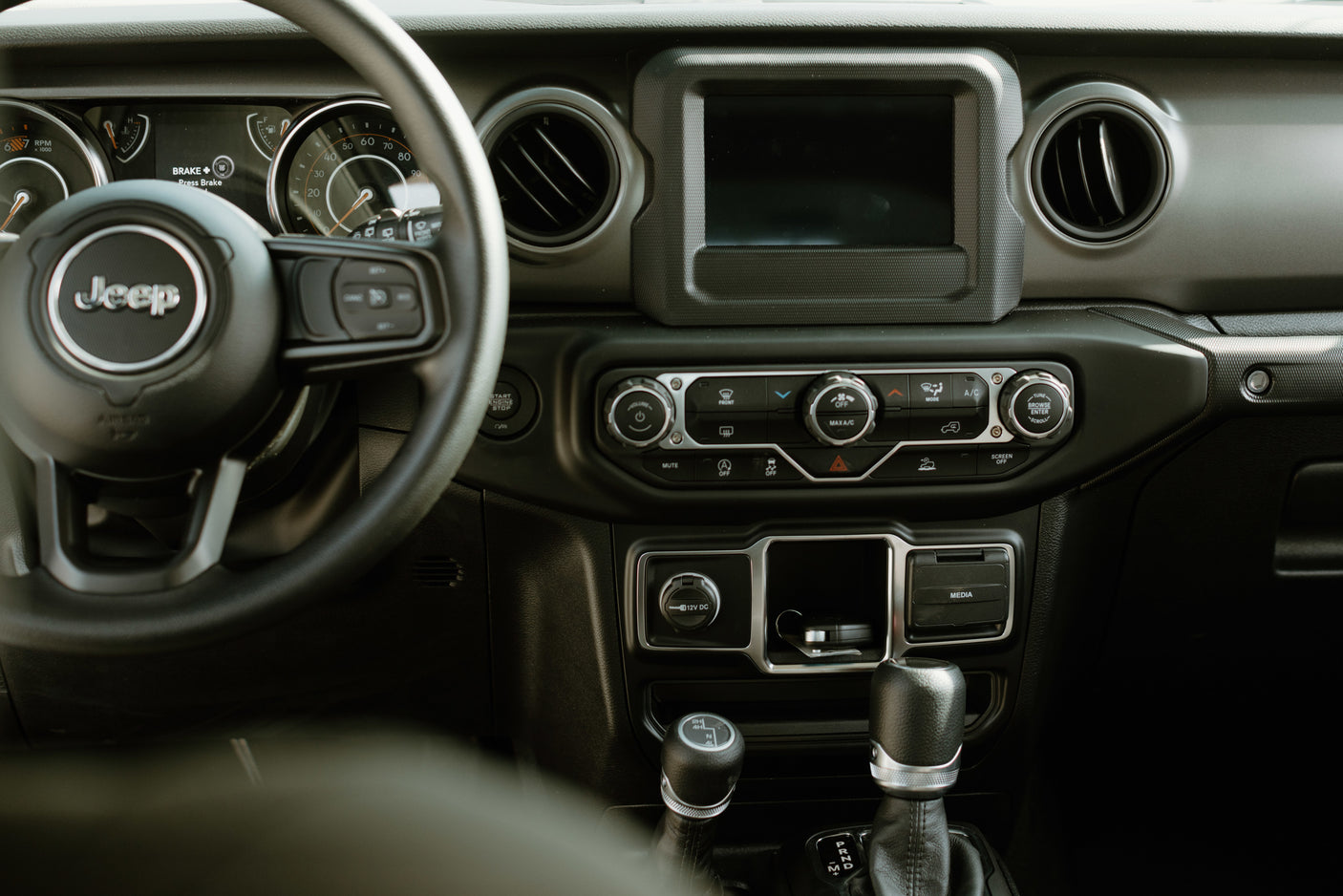 Jeep interior showing dashboard, steering wheel, screen, and shifters. Perfect for exploring, like a rugged rv rental adventure.