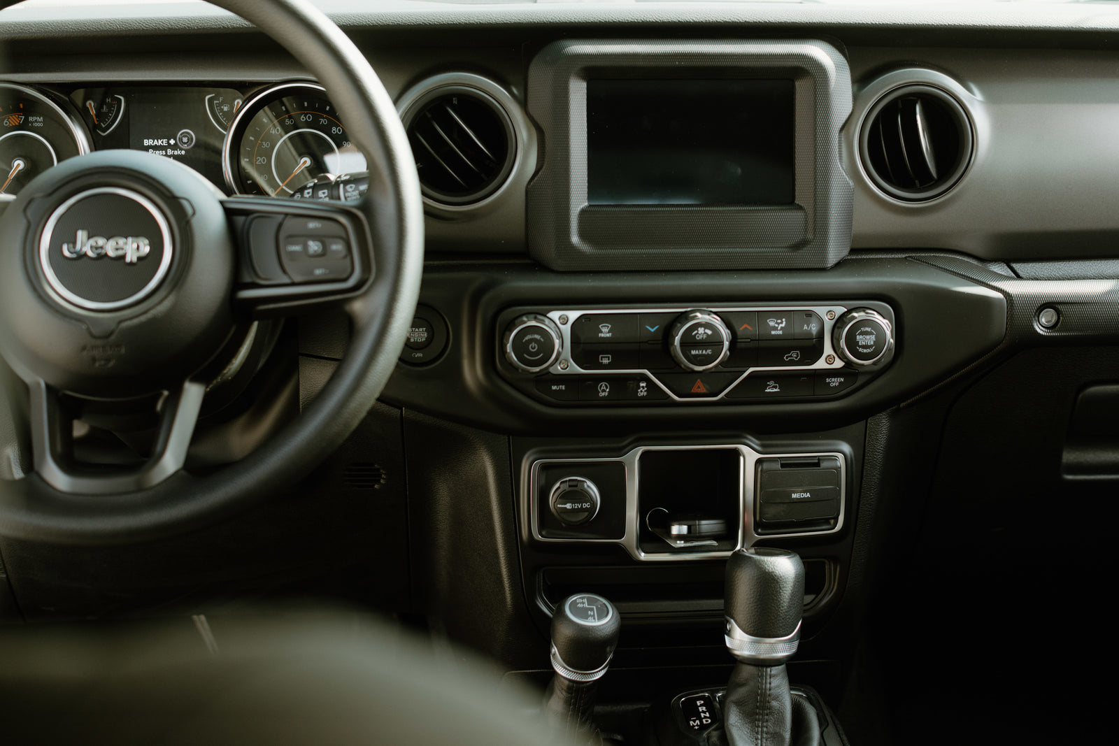 Jeep interior showing dashboard, steering wheel, screen, and shifters. Perfect for exploring, like a rugged rv rental adventure.