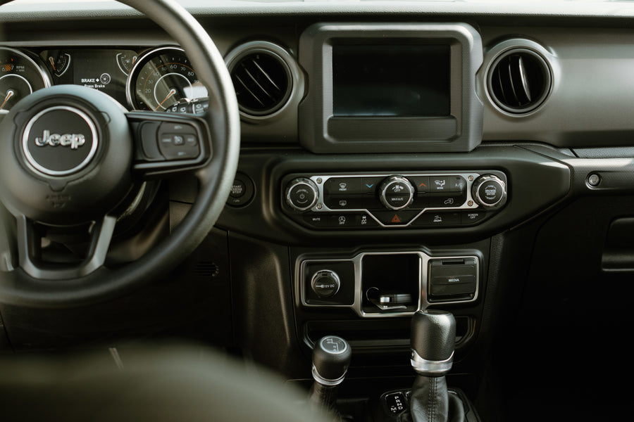 Jeep interior showing dashboard, steering wheel, screen, and shifters. Perfect for exploring, like a rugged rv rental adventure.