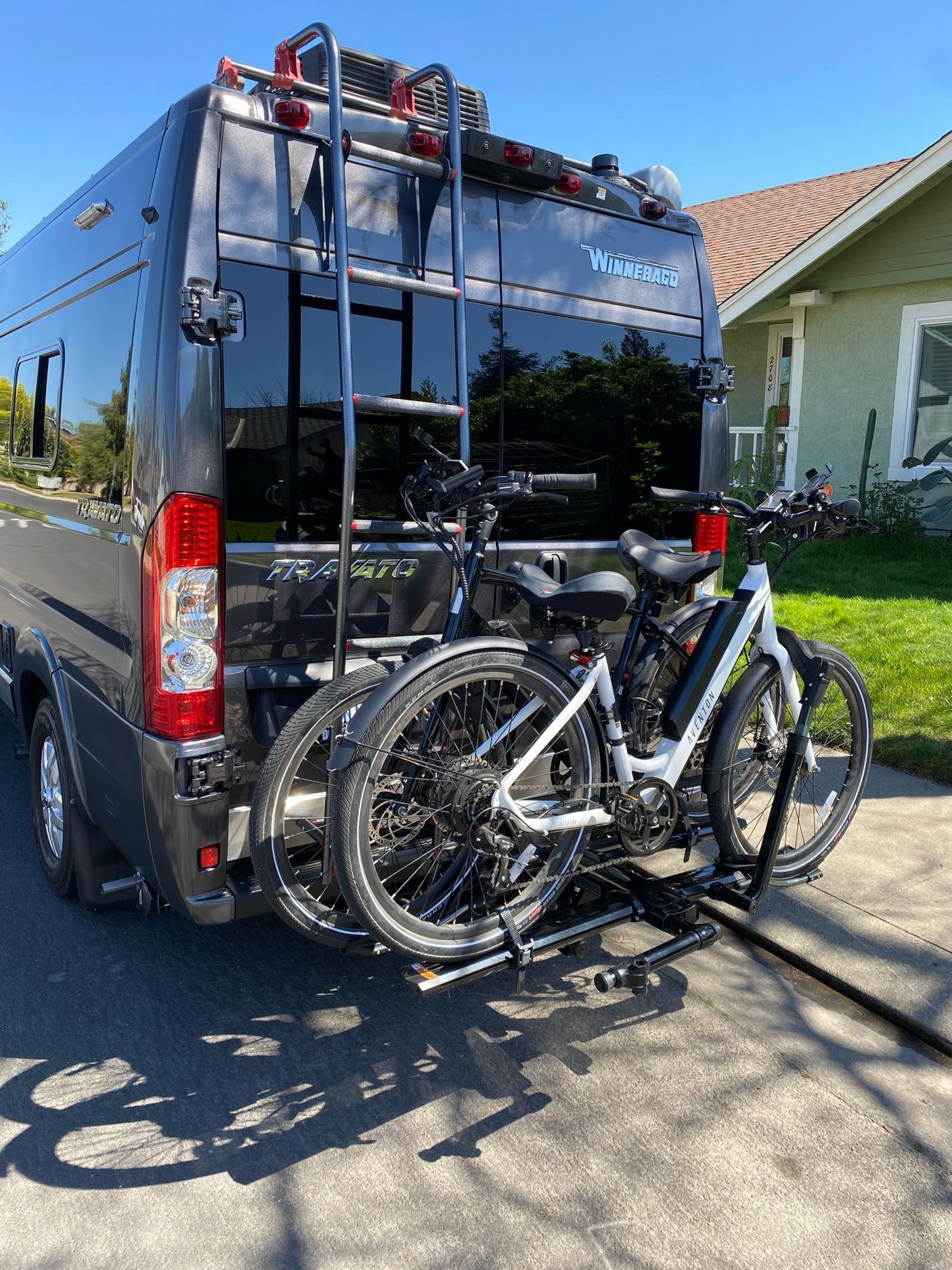 Winnebago Travato RV rental with two e-bikes on a rear rack, parked outside, ready for travel.