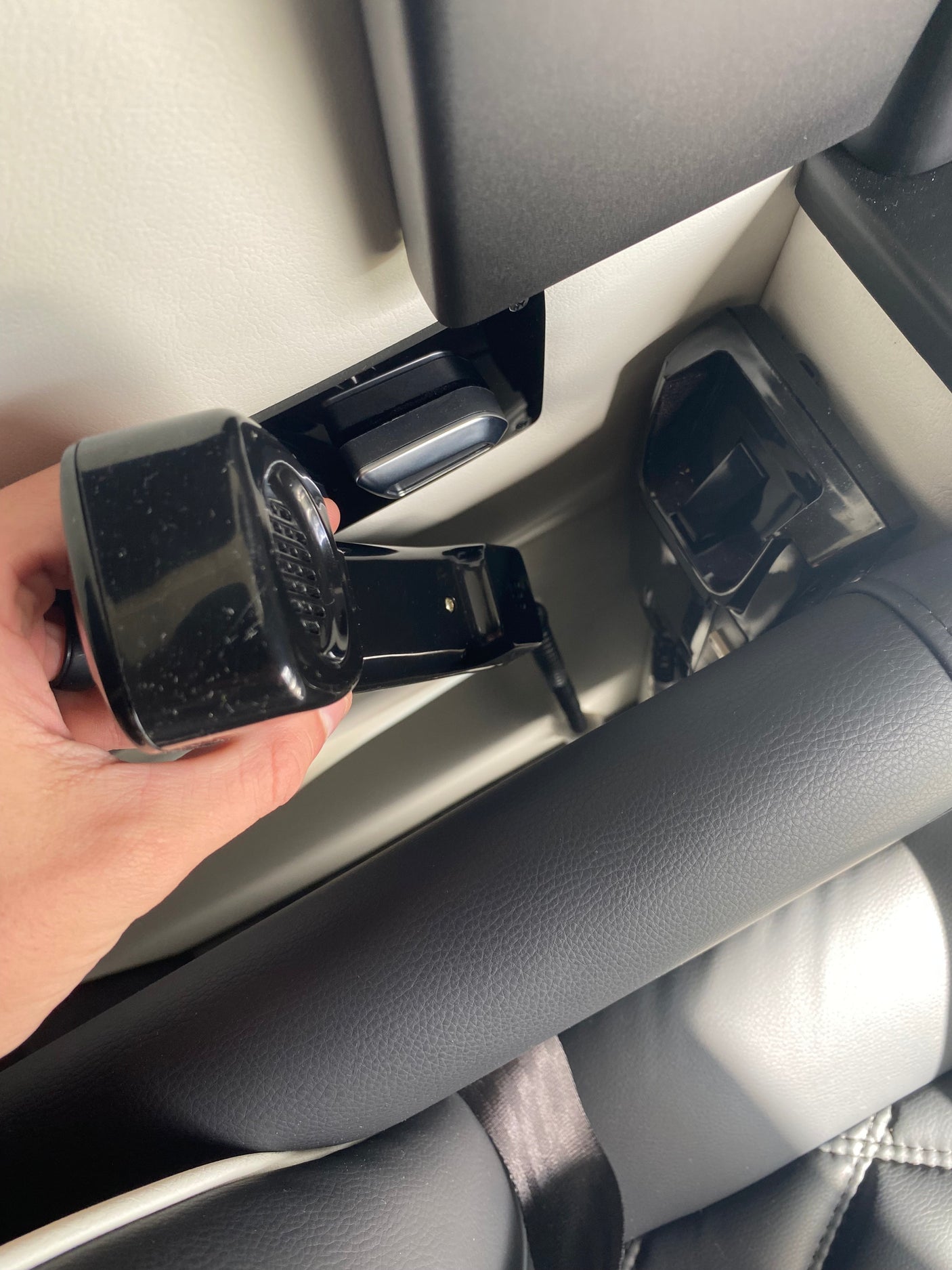 A hand connects a black seat belt buckle to its receiver in a modern RV rental interior, ensuring passenger safety.