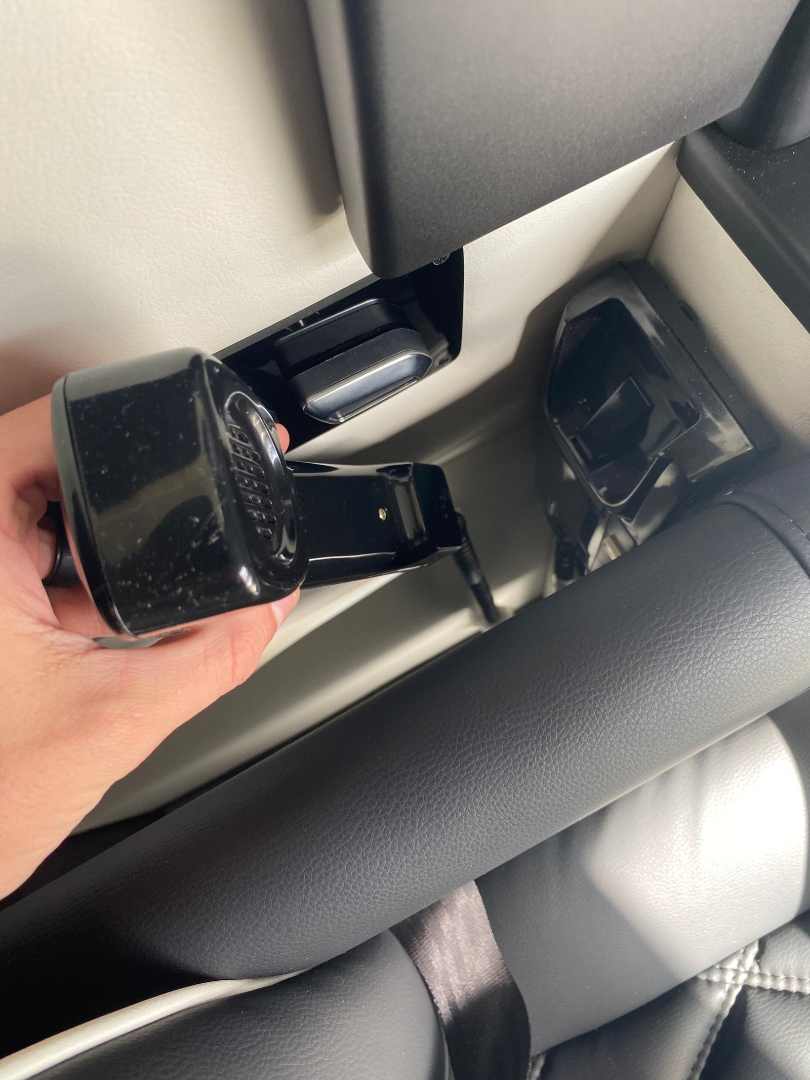 A hand connects a black seat belt buckle to its receiver in a modern RV rental interior, ensuring passenger safety.