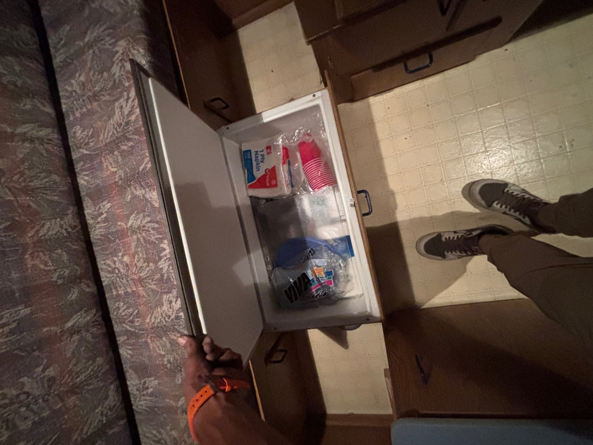 showing controls and vents for cooling the camper interior.|RV rental interior: compact camper kitchen and dining space with a stove — photo 12