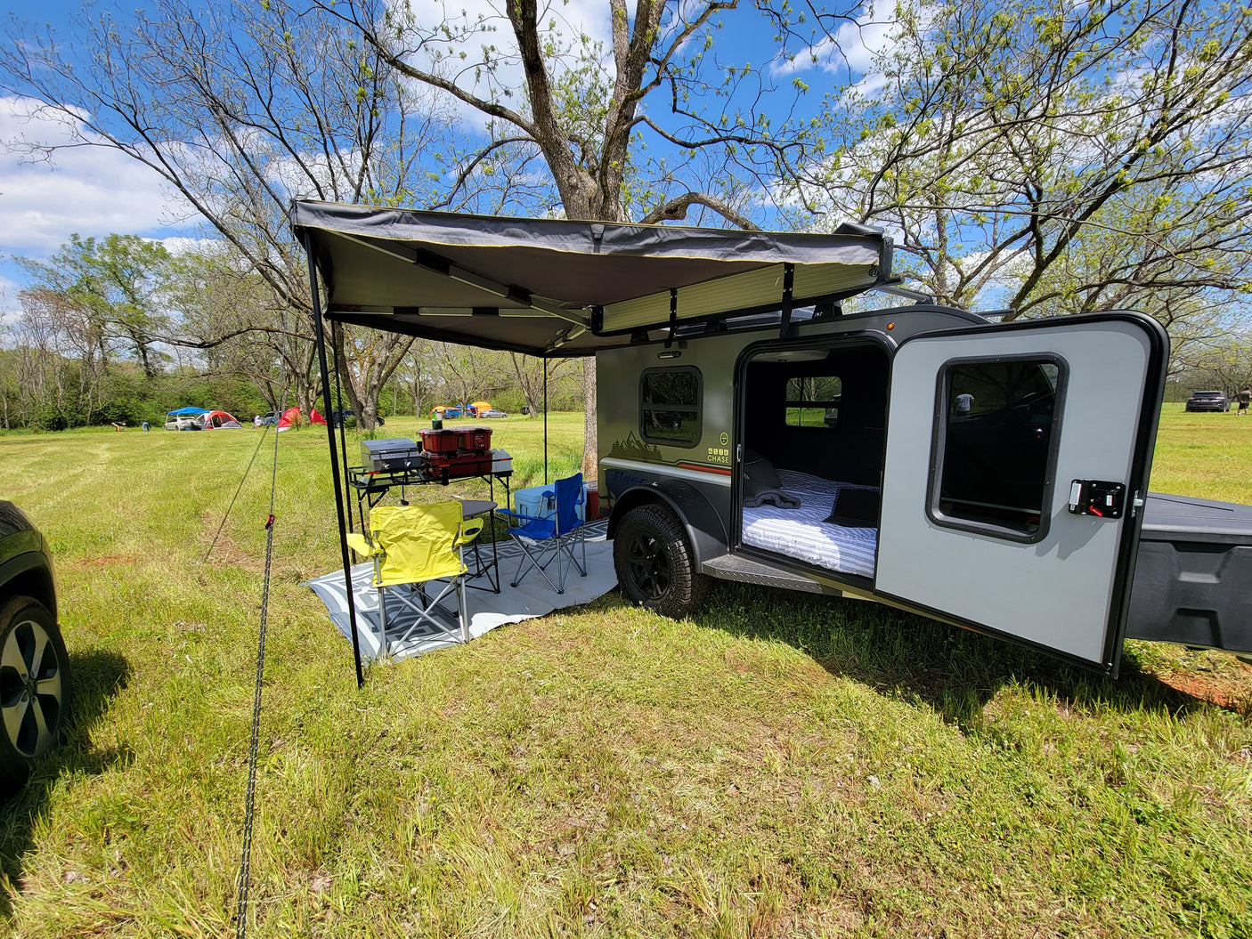 A cozy RV rental teardrop trailer with an awning setup for comfortable camping outdoors.