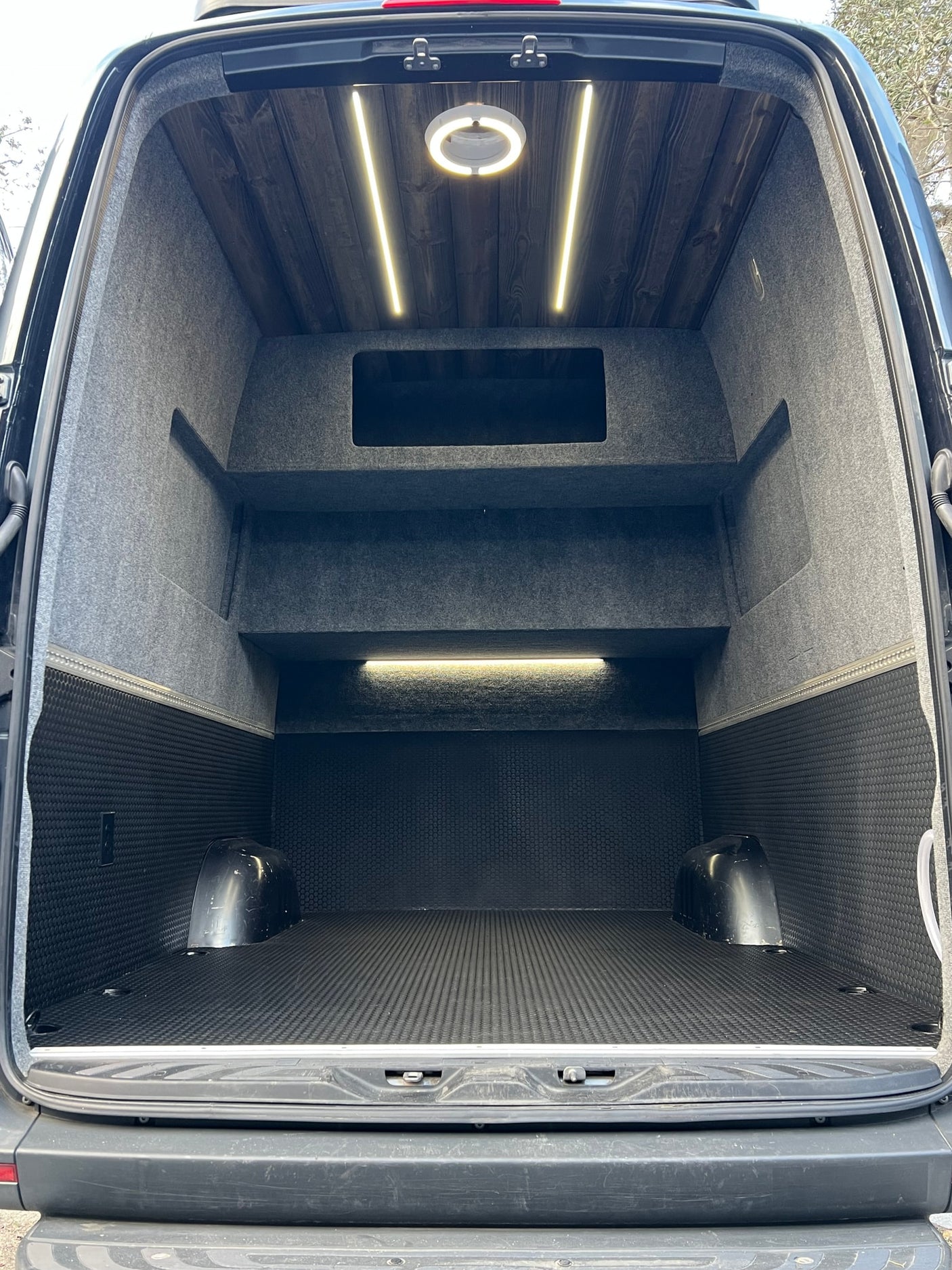 RV rental van's organized cargo space: wood ceiling, shelving, textured floor, and bright lighting.
