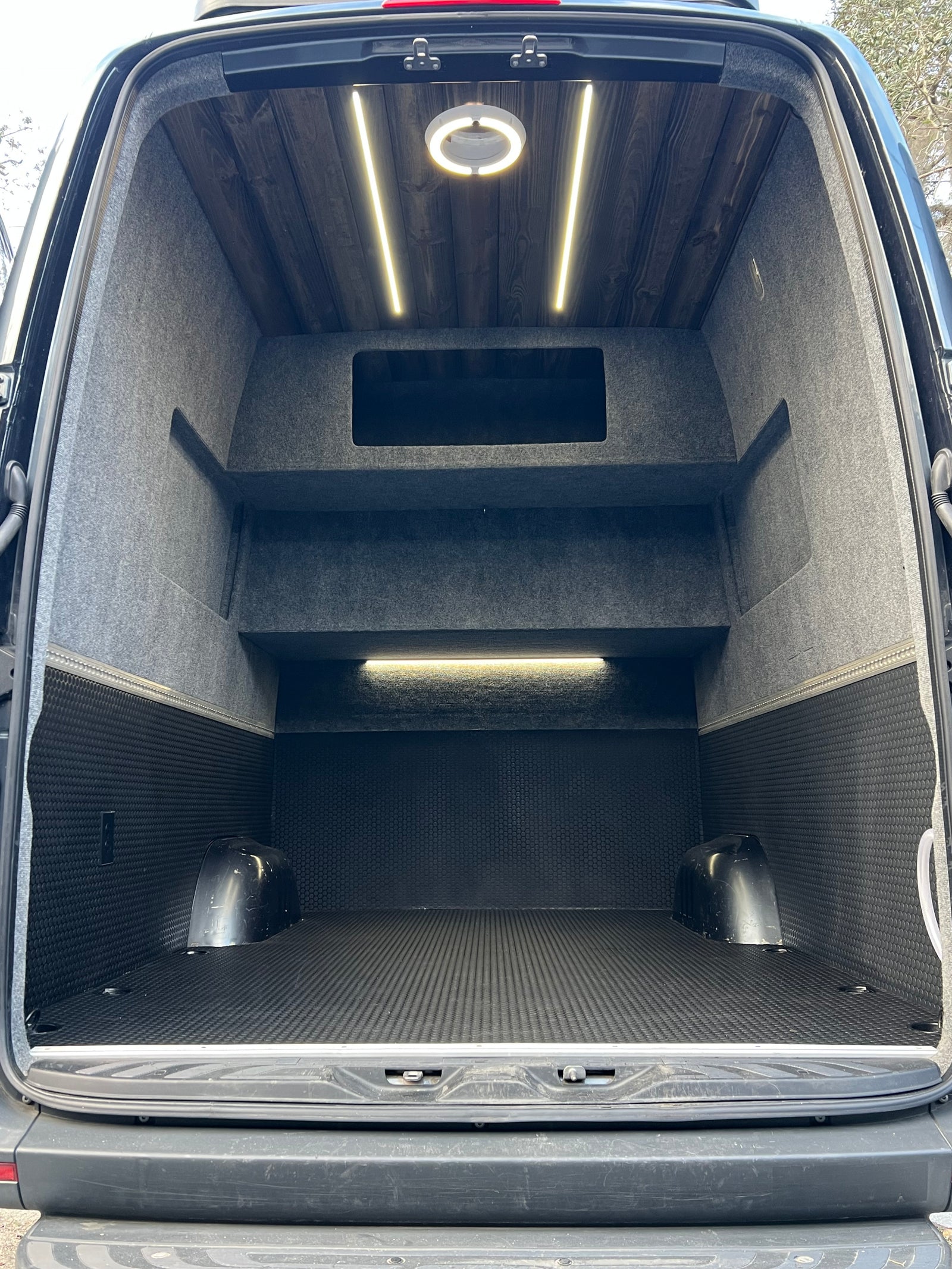RV rental van's organized cargo space: wood ceiling, shelving, textured floor, and bright lighting.