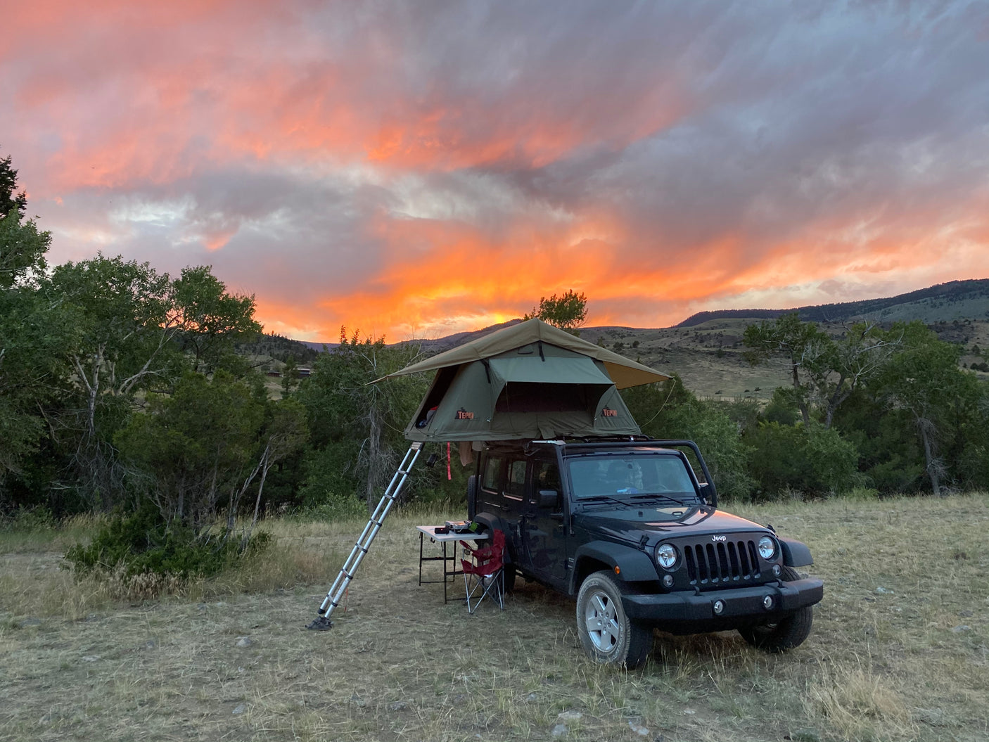 Jeep Wrangler with a rooftop tent set up at golden hour, a great RV rental alternative for camping.