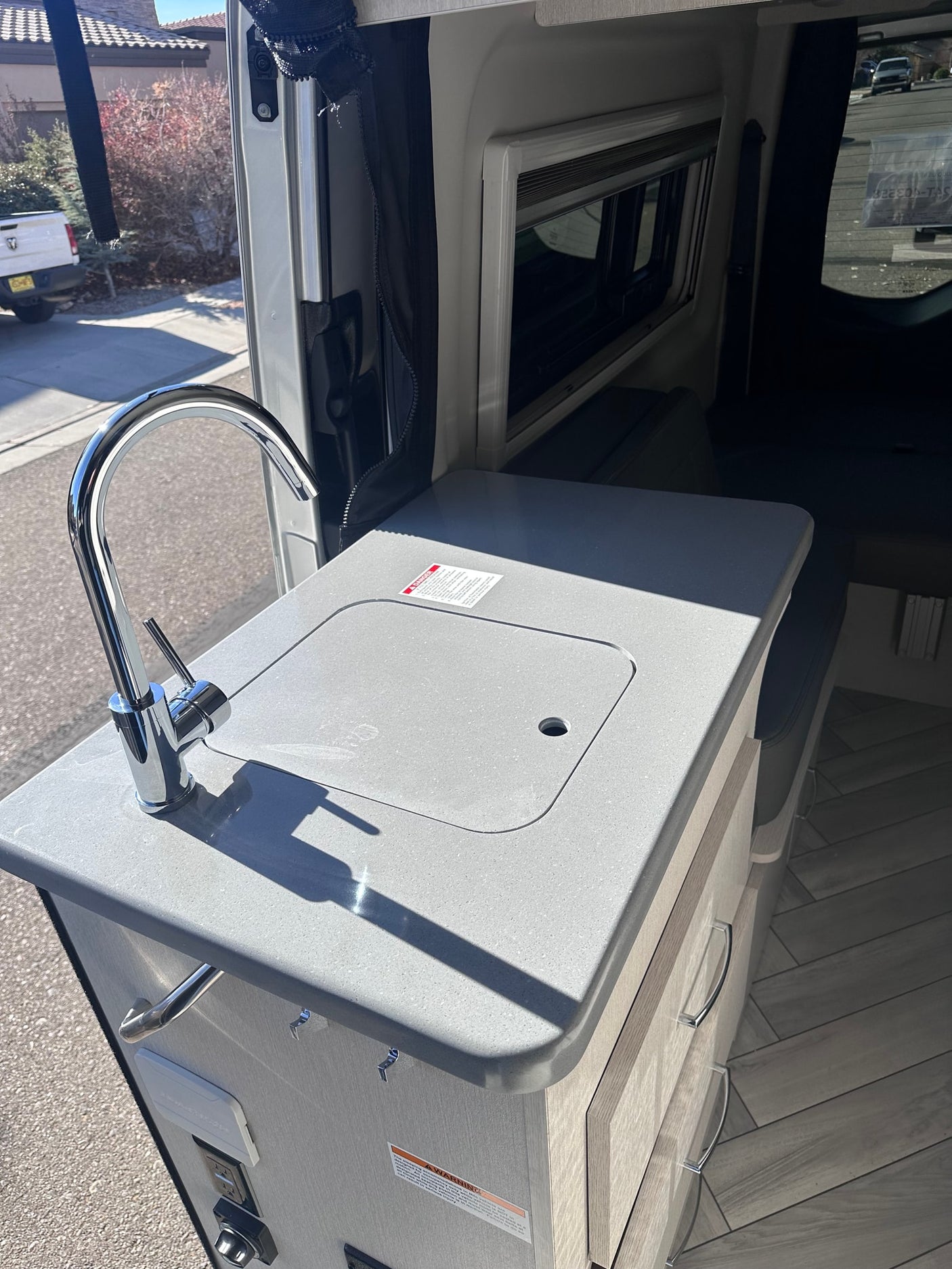 & digital dash.|RV rental's side door reveals a compact kitchen with a sink